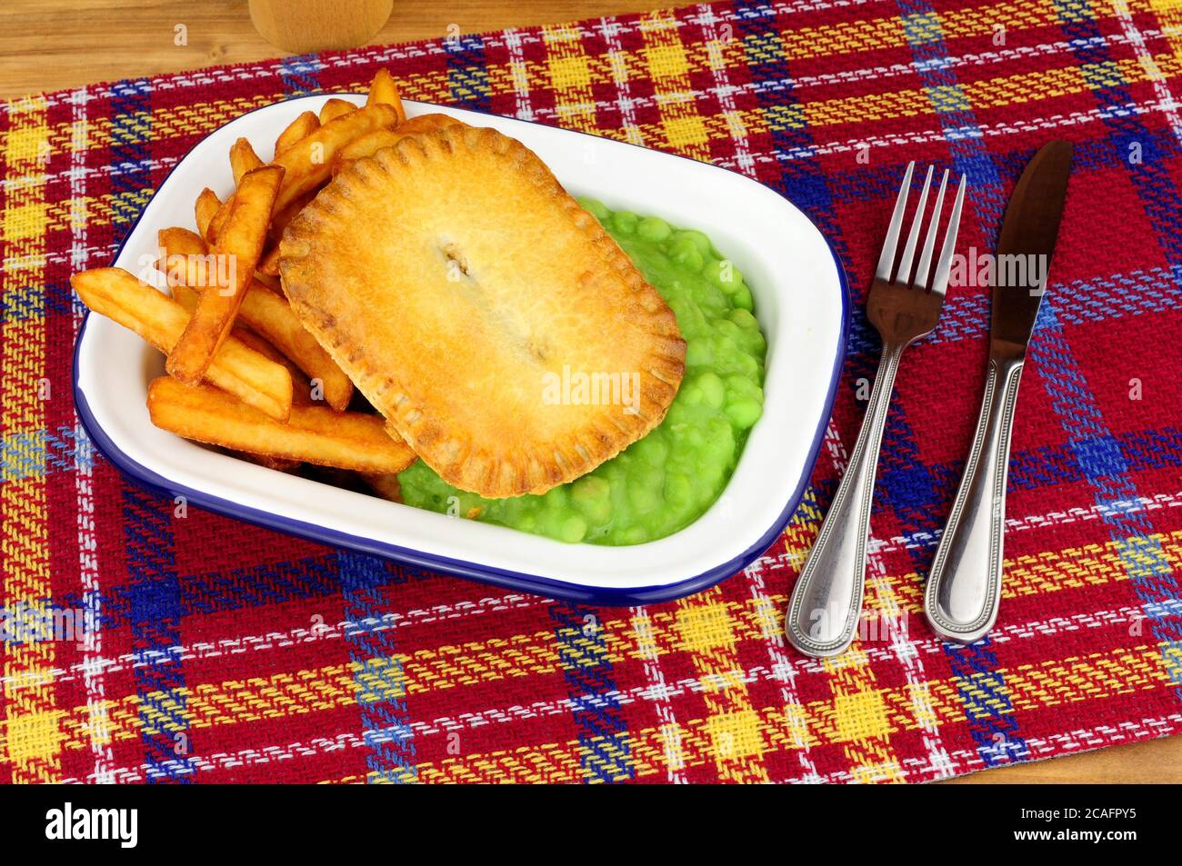 Steak und Kidney Pie und Chips Mahlzeit mit matschigen Erbsen In einer Metall-Emaille-Schale Stockfoto