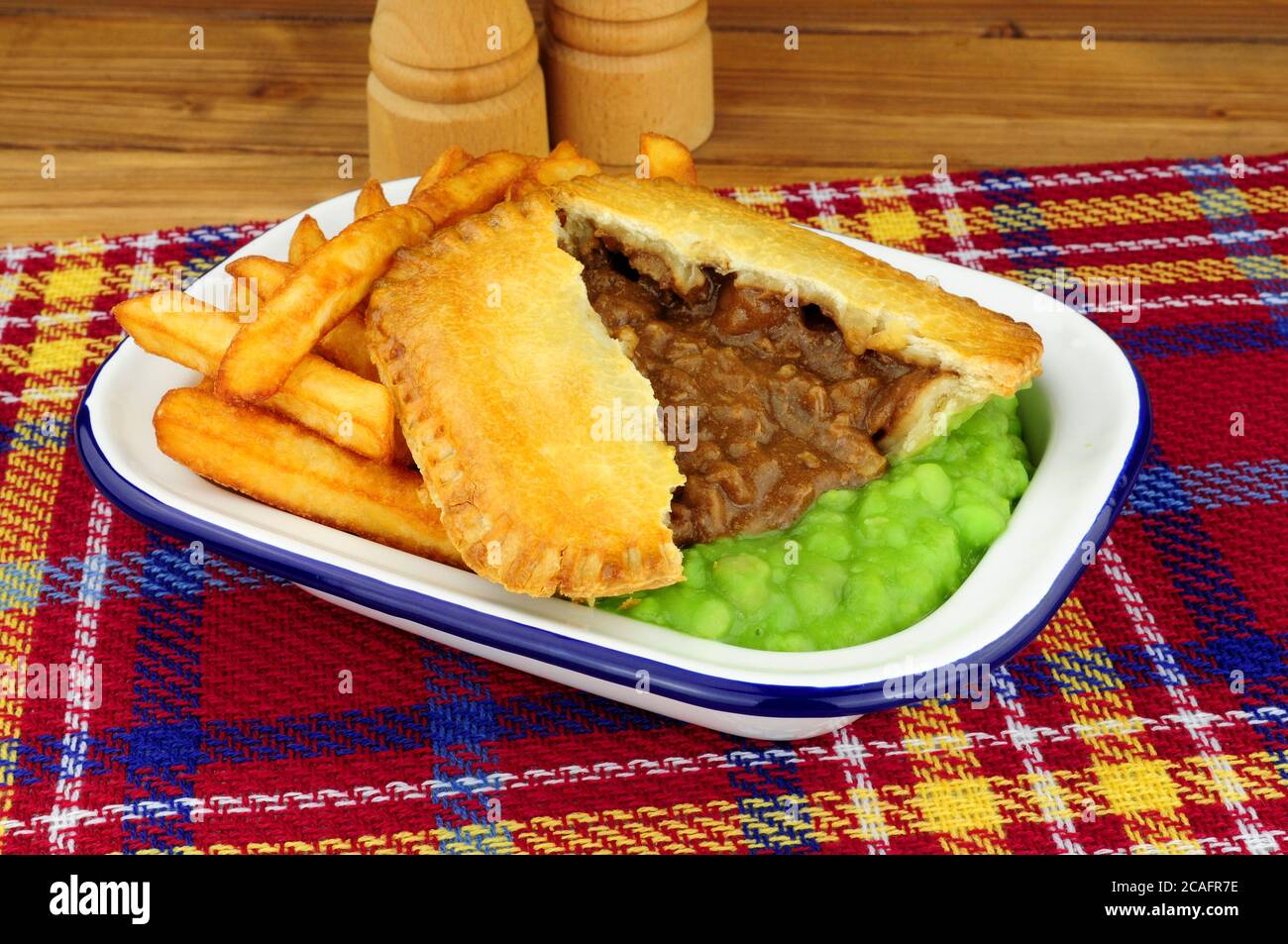 Steak und Kidney Pie und Chips Mahlzeit mit matschigen Erbsen In einer Metall-Emaille-Schale Stockfoto