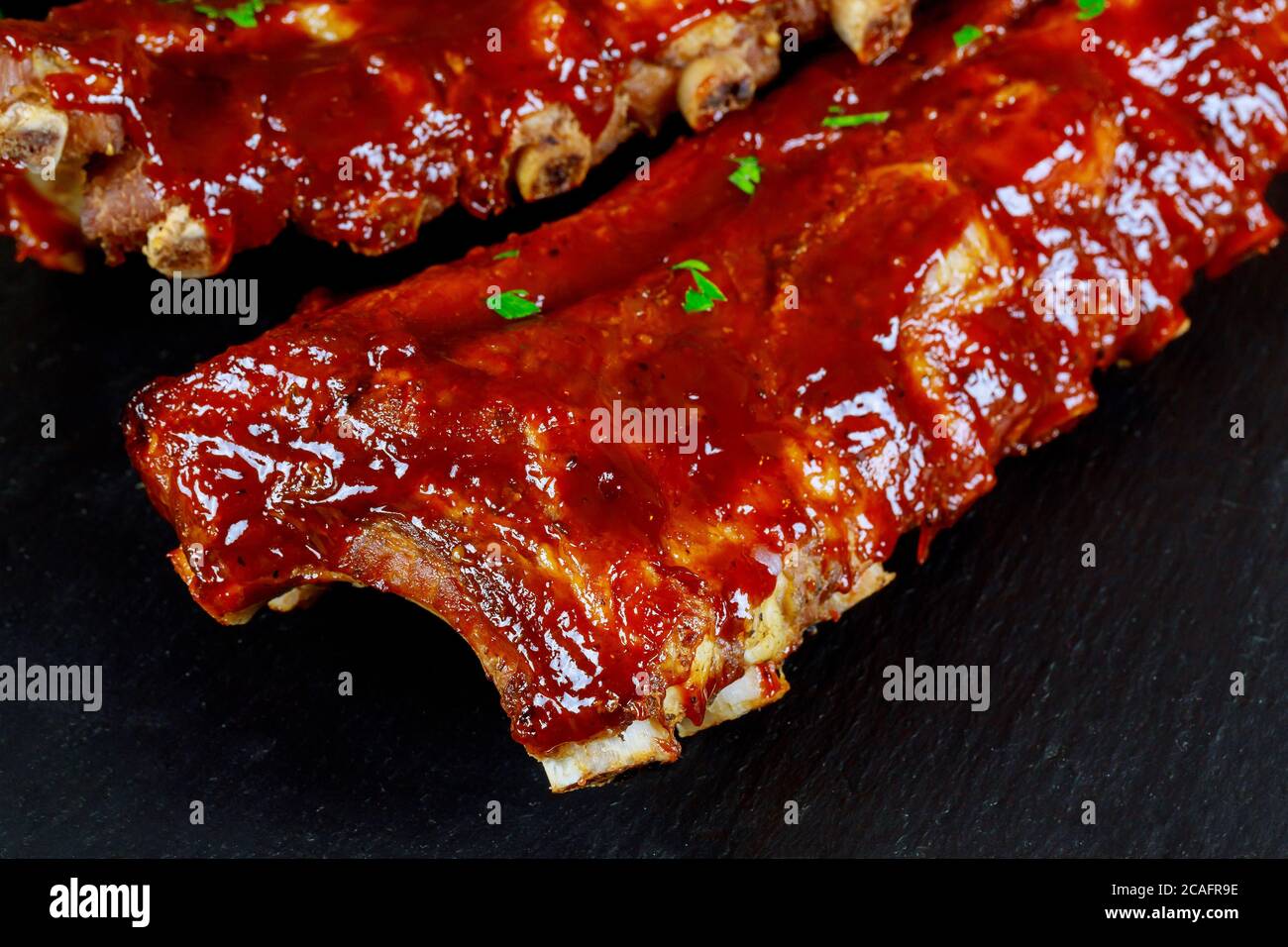 BBQ Schweinefleisch Spare Ribs auf schwarzem Brett Nahaufnahme. Stockfoto