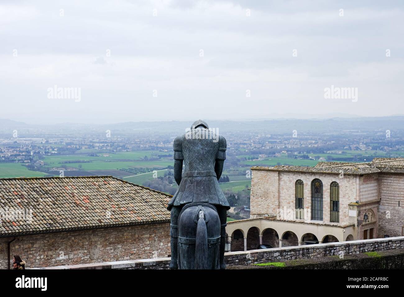 Assisi, italien - juni 30 2020: Berühmte Bronzeskulptur vor der kirche des heiligen franz von Assisi über der alten Stadtlandschaft, italien Stockfoto