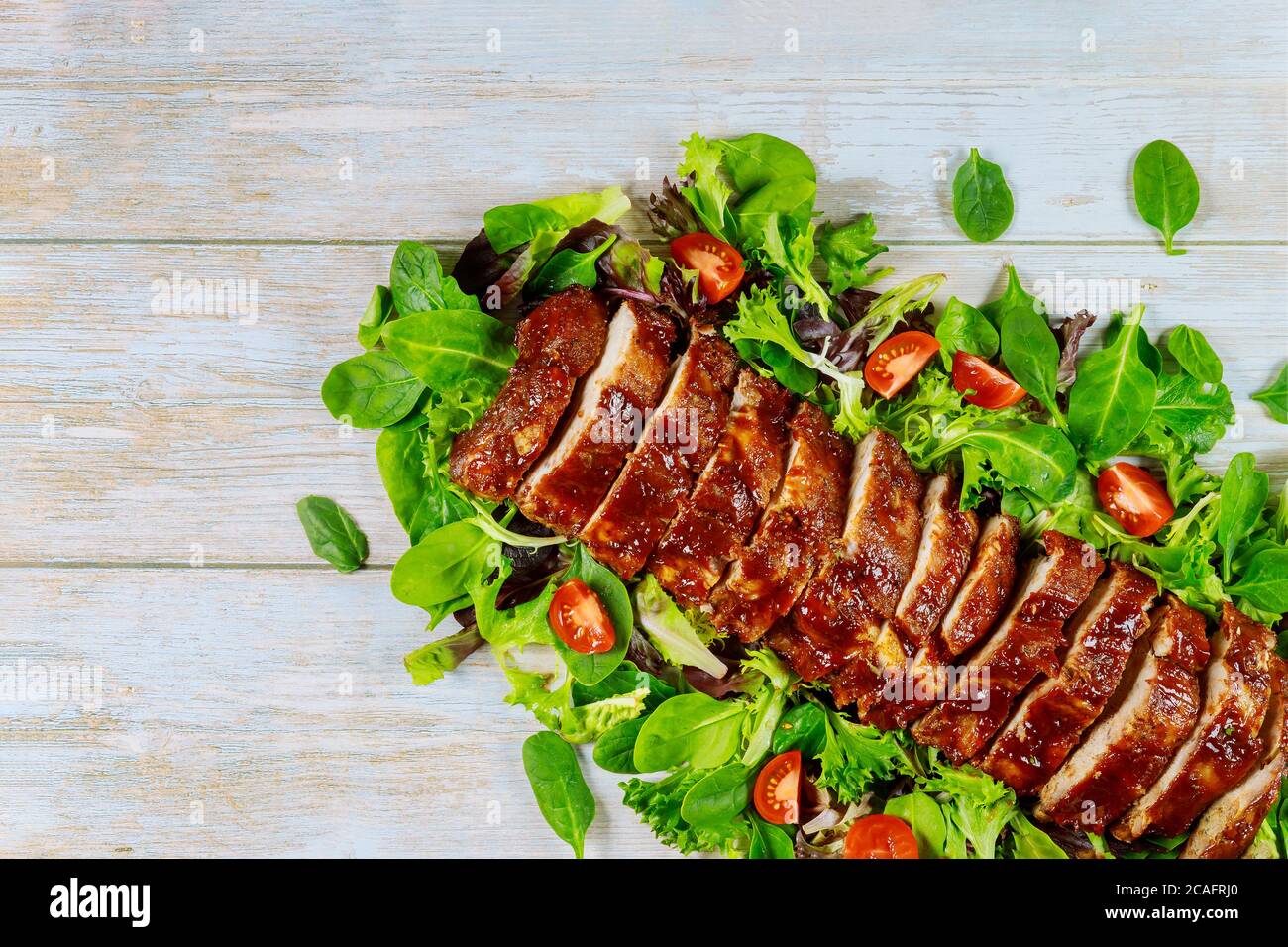 Gegrillte Spare Baby Back Ribs mit grünem Salat und Tomate. Stockfoto