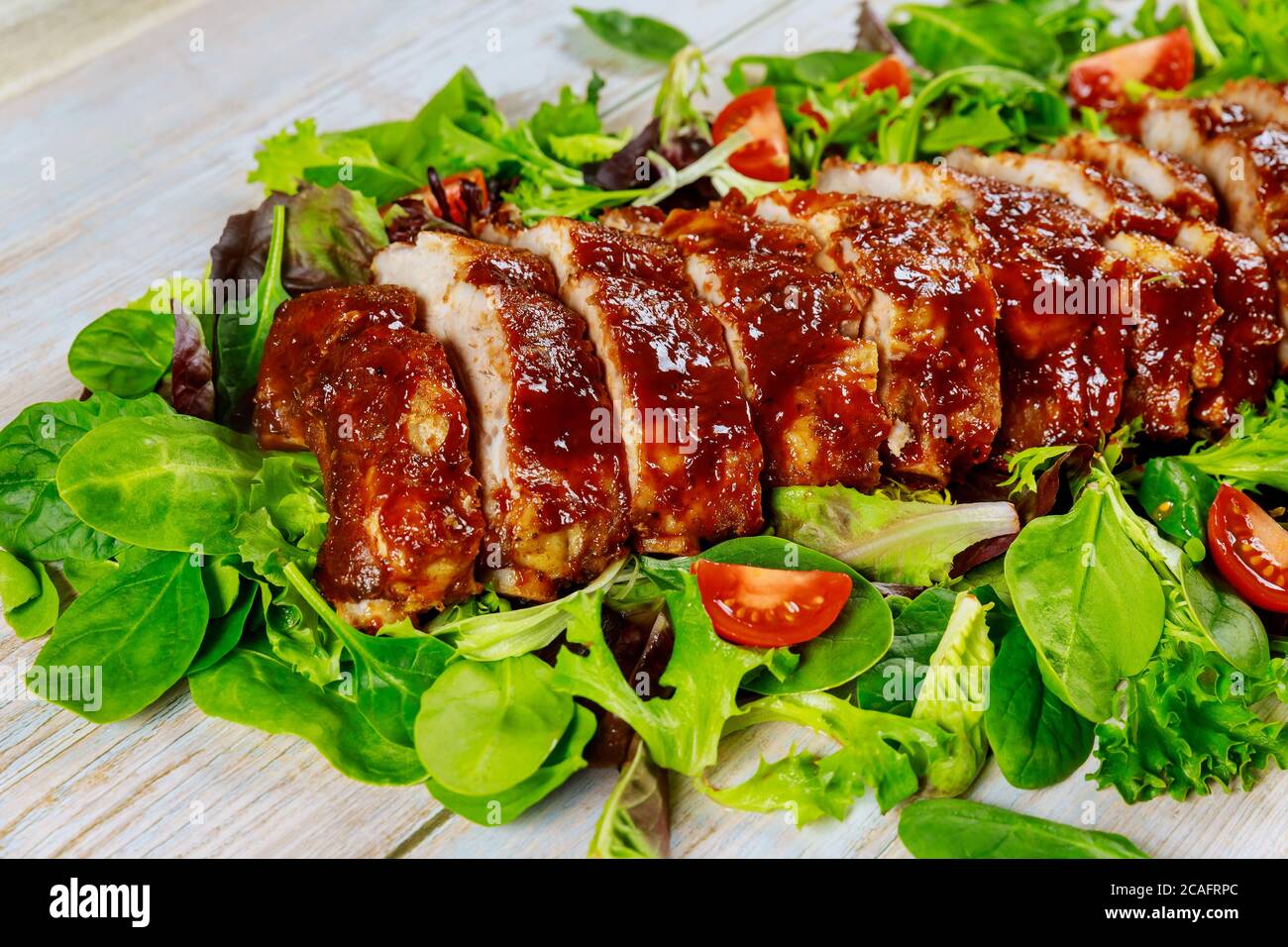 Leckere BBQ-Rippchen mit Tomaten, grünem Salat und würziger BBQ-Sauce. Stockfoto