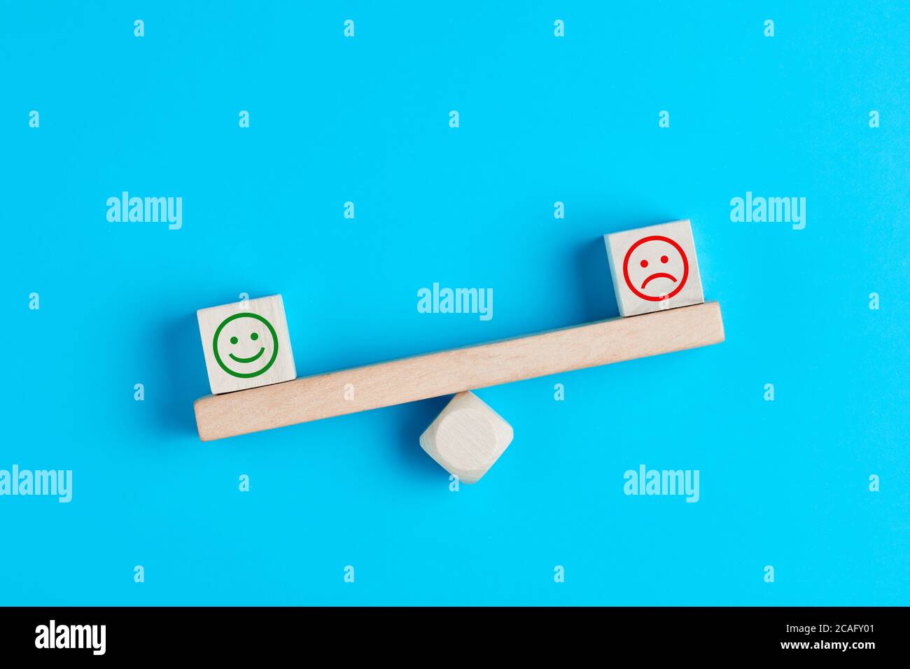 Fröhliche und traurige Smiley-Gesichter auf hölzerner Wippe. Kundenzufriedenheit, Bewertung oder positives Feedback-Konzept. Stockfoto