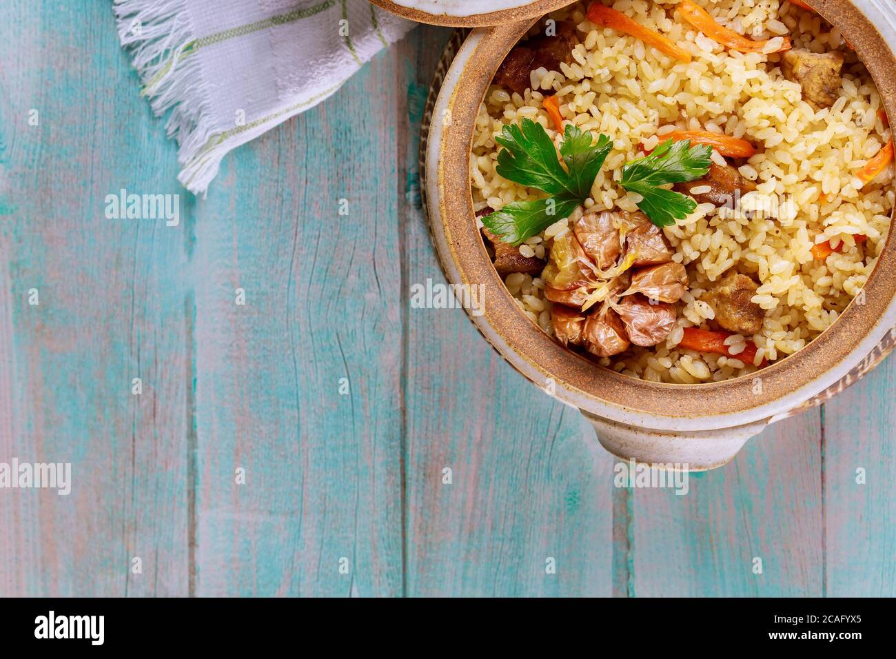Chinesischer Reis mit Gemüse und Fleisch in Tontopf auf Holzgrund. Stockfoto