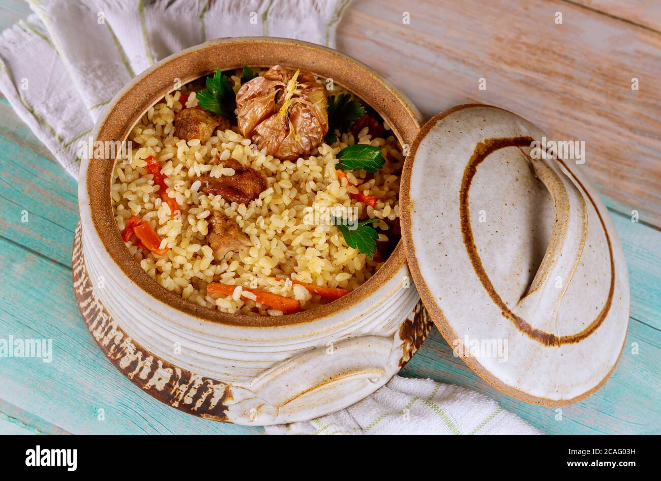Reispilaf mit Lamm, Karotten, Knoblauch und indischen Gewürzen in Tontopf mit Deckel. Stockfoto