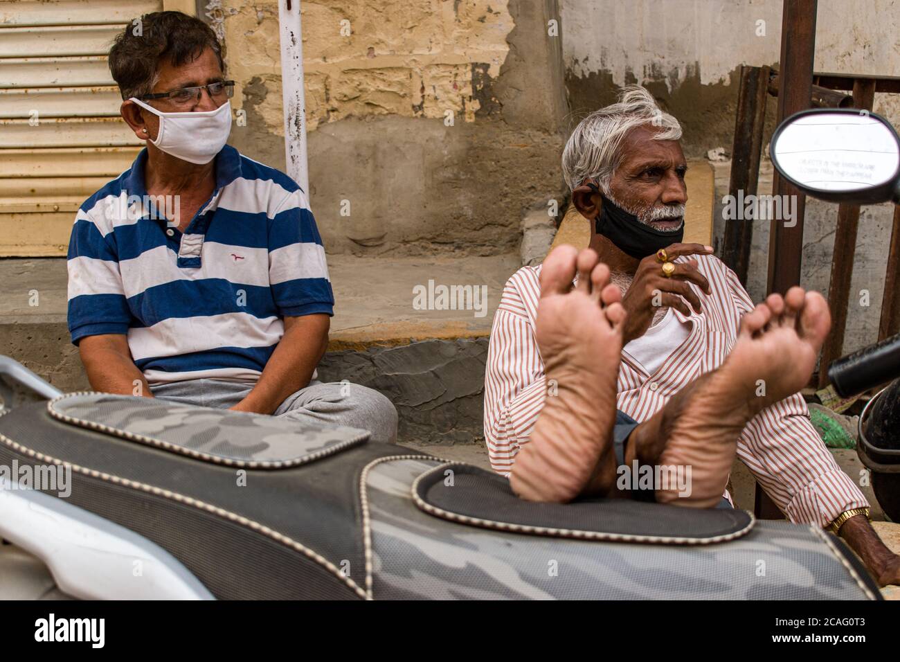 jaisalmer, rajasthan / indien - juli 22 2020 : zwei Männer mittleren Alters entspannen sitzend Beine auf dem Fahrzeug Blick auf ihre linke Seite Stockfoto