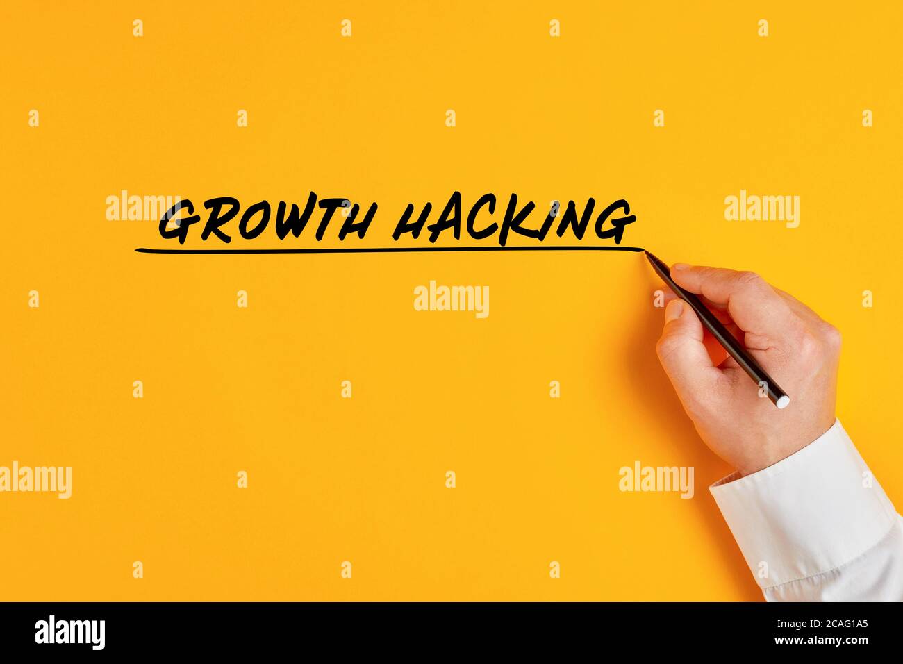 Männliche Hand schreibt das Konzept des Wachstums Hacking auf gelbem Hintergrund. Growth Hacking impliziert ein massives Wachstum in kurzer Zeit mit einem kleinen Budget in Stockfoto