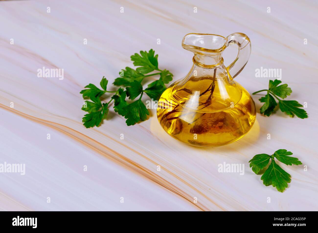 Kräuter Olivenöl extra vergine in Glasflasche mit Rosmarin und Petersilie. Stockfoto