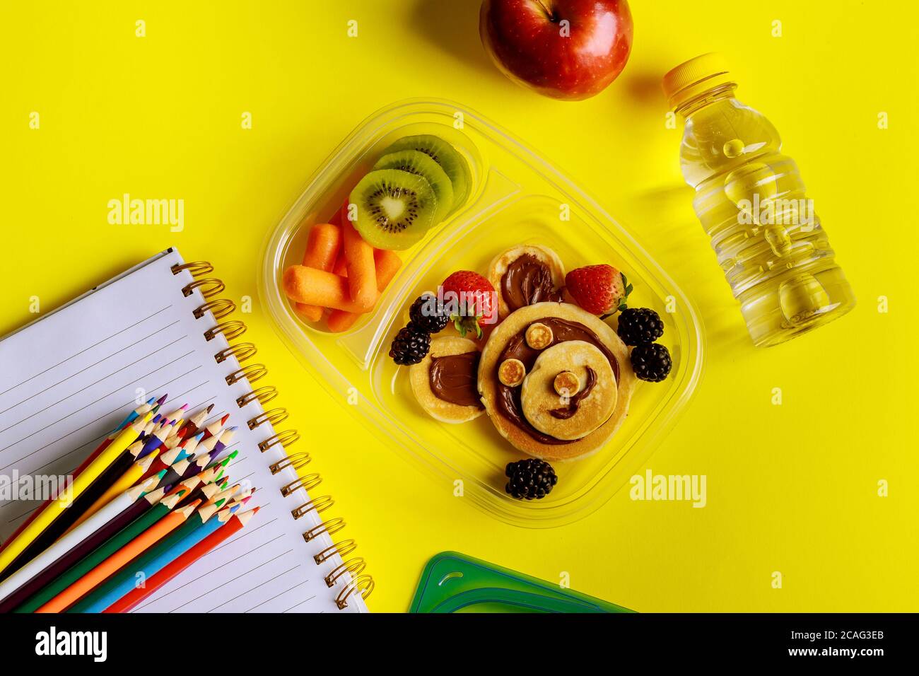 Schullunch-Box mit Pfannkuchen, frischem Obst und einer Flasche Wasser mit Vorräten. Zurück zur Schule Konzept. Stockfoto