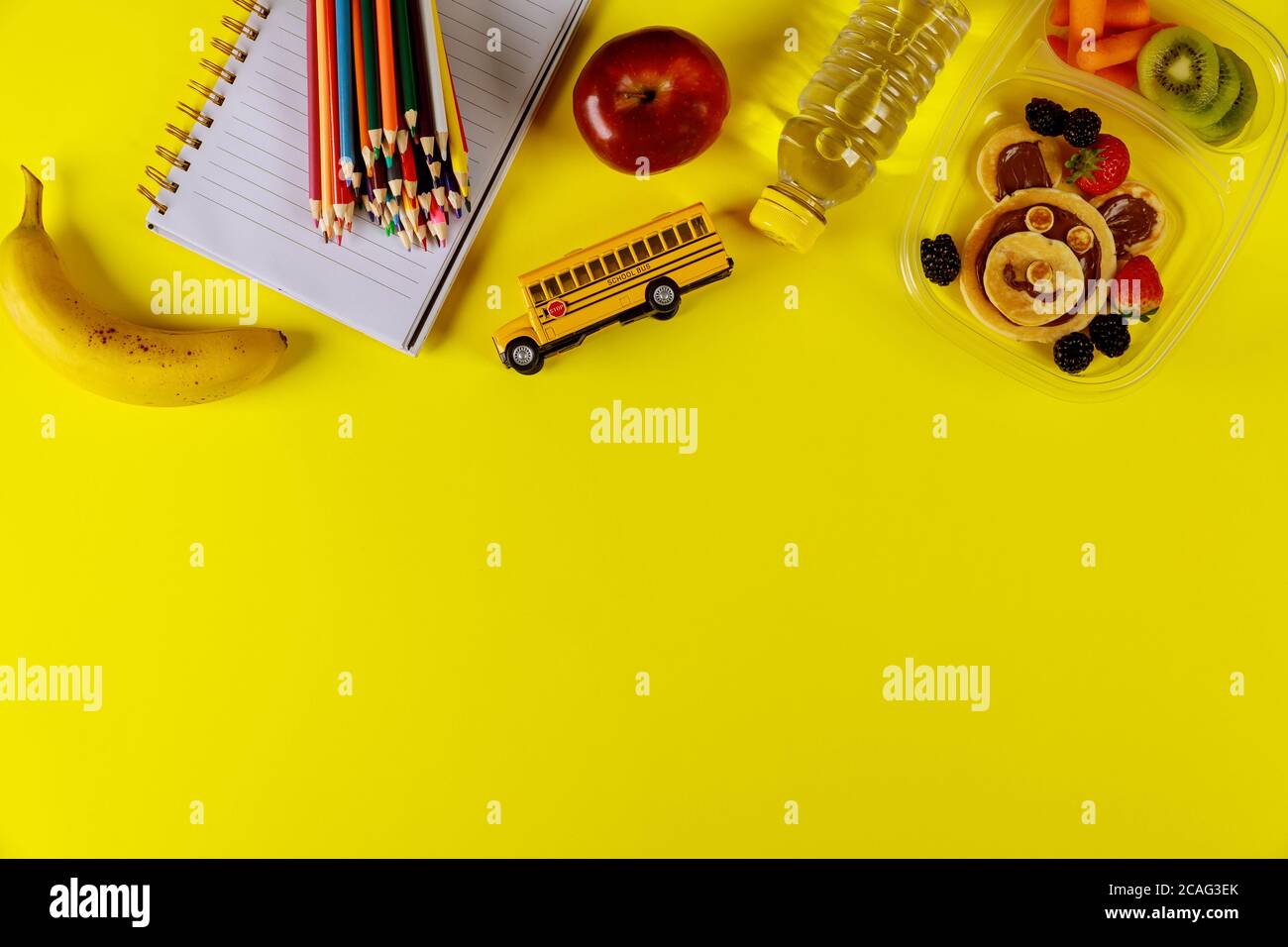 Zurück zur Schule Konzept. Lunchbox mit Pfannkuchen, Karotte, Apfel und Banane mit Kinderschrubben. Draufsicht, Kopierbereich. Stockfoto