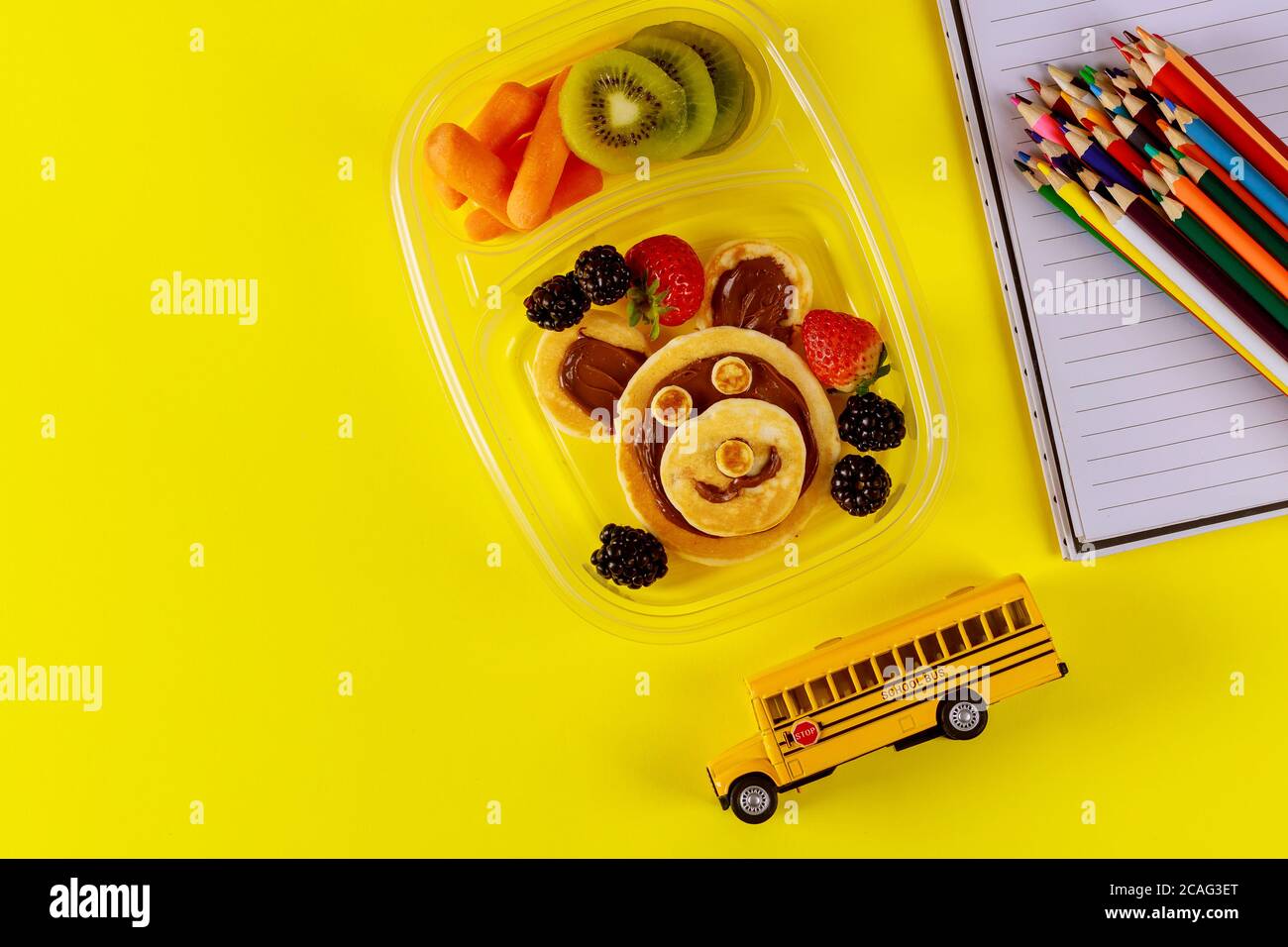 Schulspeisedose mit Pfannkuchen, frischem Obst und Schulbusspielzeug mit Vorräten. Zurück zur Schule Konzept. Stockfoto