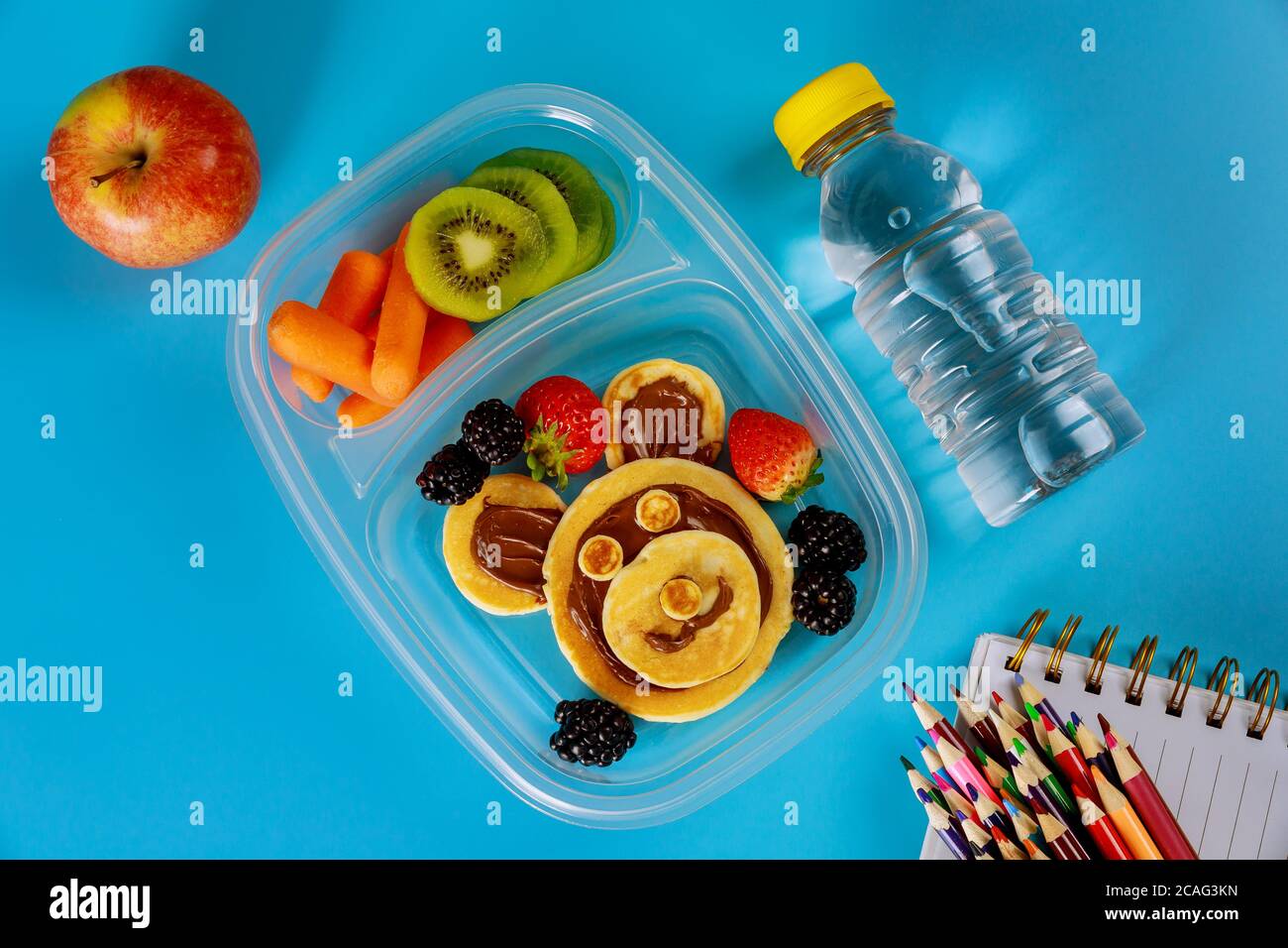 Schullunch-Box mit Pfannkuchen, frischem Obst und einer Flasche Wasser mit Vorräten. Zurück zur Schule Konzept. Stockfoto