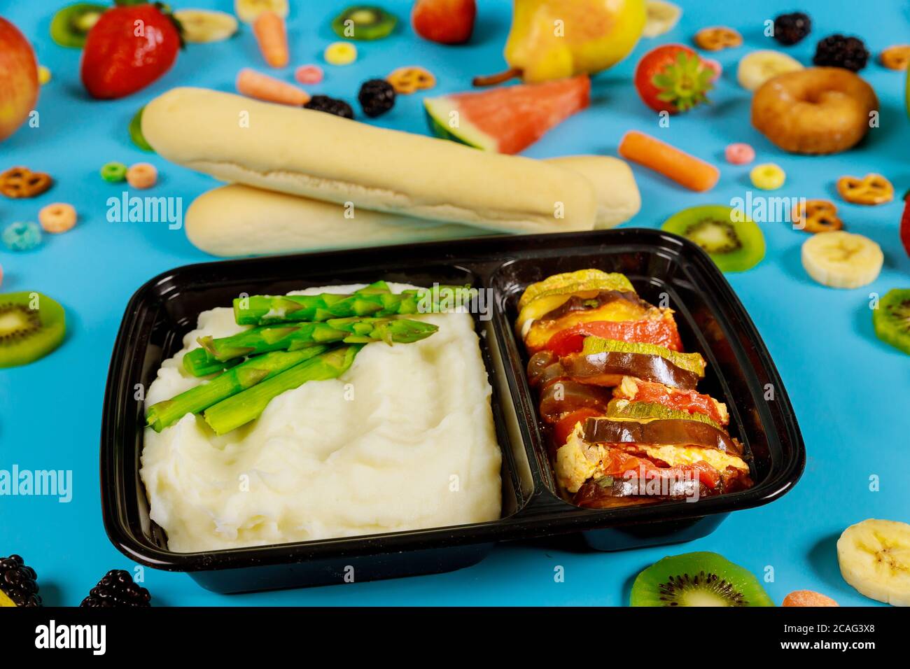 Leckeres Mittagessen in einem Behälter. Kartoffelpüree mit Spargel, Gemüse und Brotstock. Stockfoto