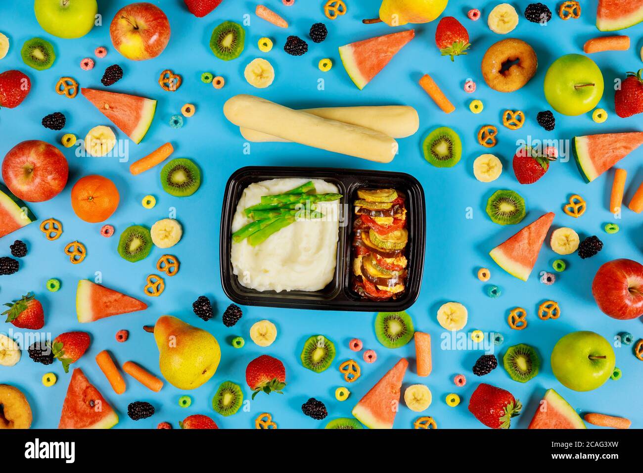 Mittagspause in einem Plastikbehälter. Kartoffelpüree mit Spargel, Gemüse und Brotstock. Stockfoto