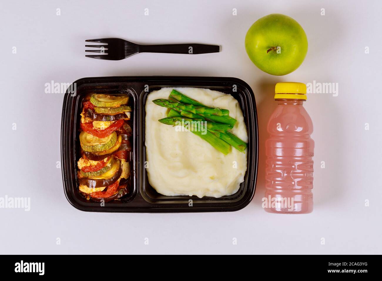 Fertiggerichte auf Lebensmittelbehälter mit Gabel, Getränk und Apfel essen. Stockfoto