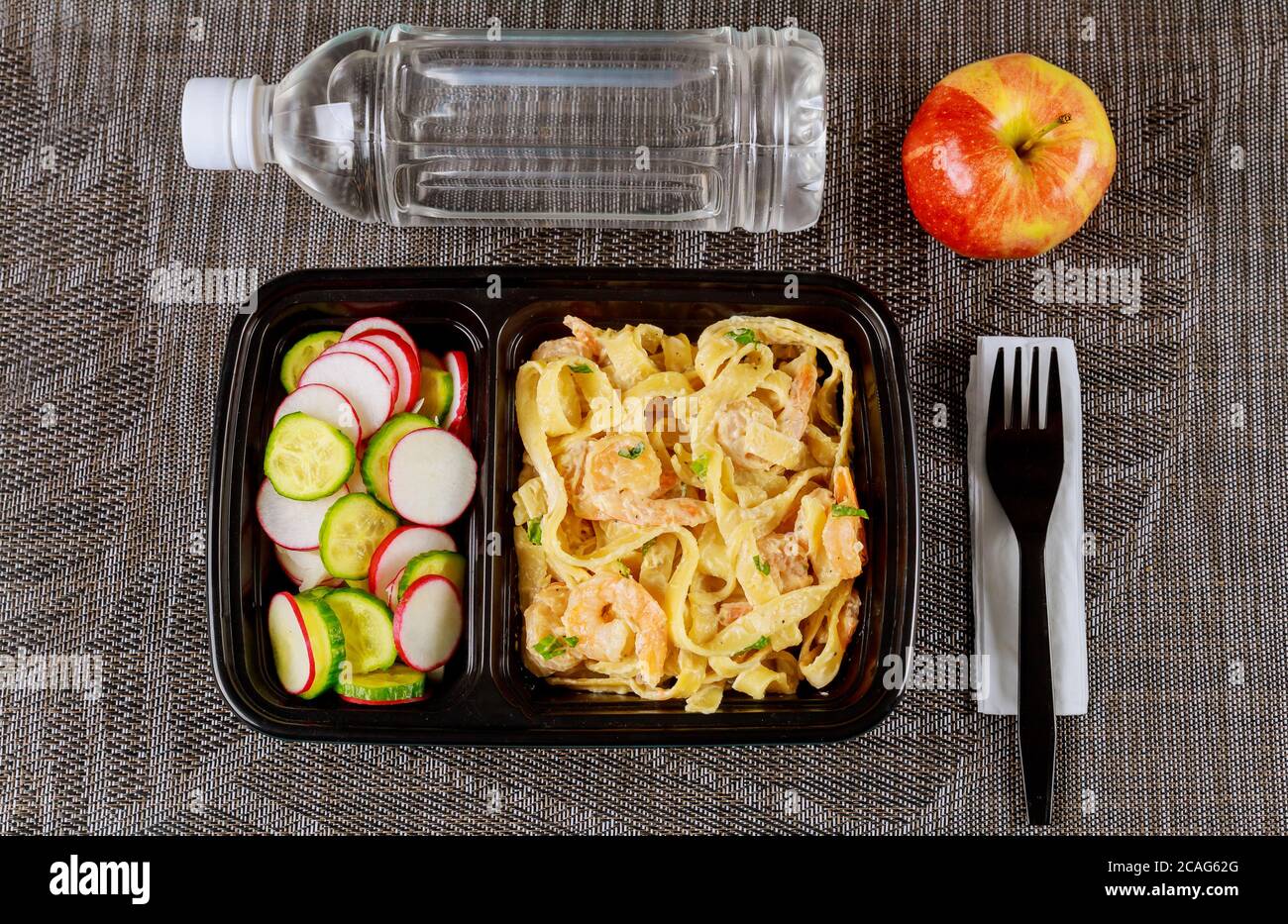 Fertiggericht auf Futterbehälter mit Gabel, Wasser und Apfel. Stockfoto