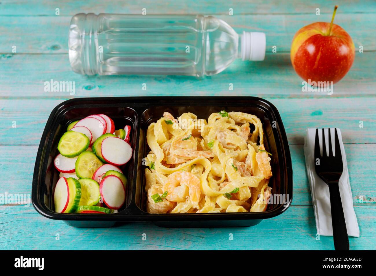 Fertiggericht auf Futterbehälter mit Gabel, Wasser und Apfel. Stockfoto