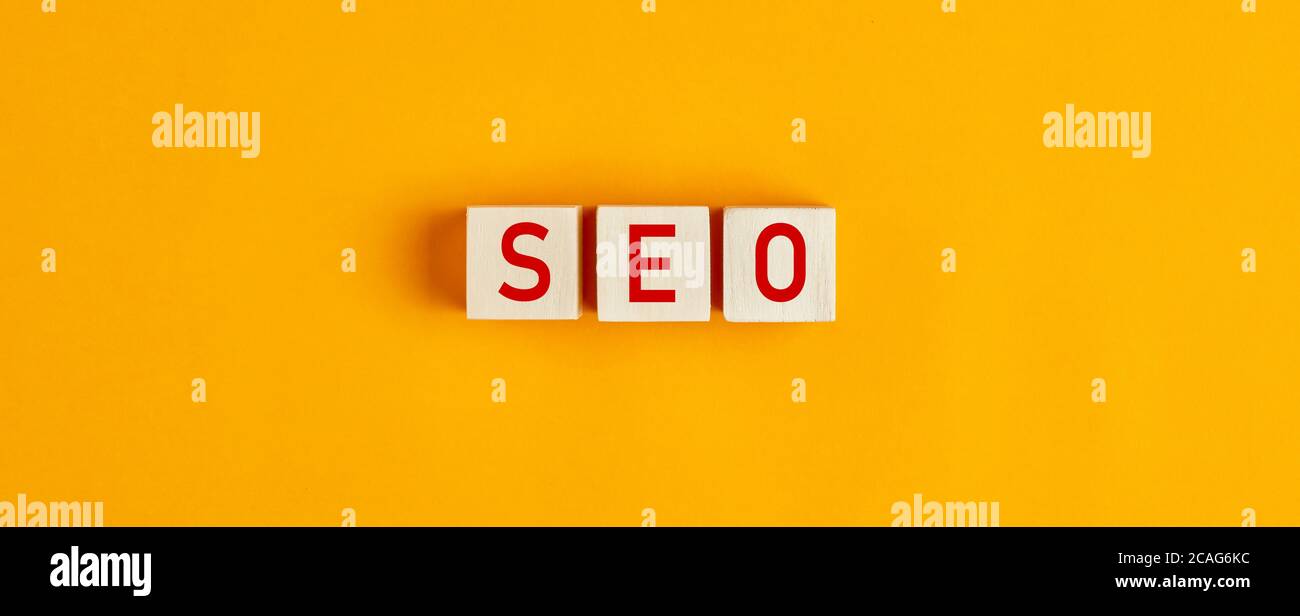 SEO (Suchmaschinenoptimierung) Buchstaben auf Holzblöcken vor gelbem Hintergrund. Flache Lay-Ansicht. Stockfoto