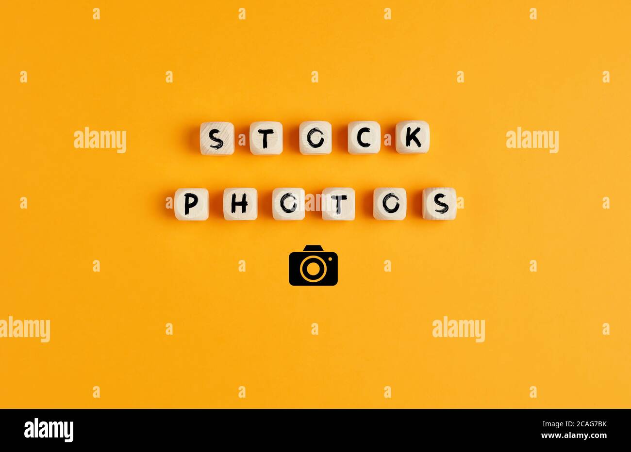 Die Wörter Stock Fotos auf Holzwürfeln mit Kamera-Symbol vor gelbem Hintergrund. Stock-Phorographie oder Phorobibliothek Konzept. Stockfoto