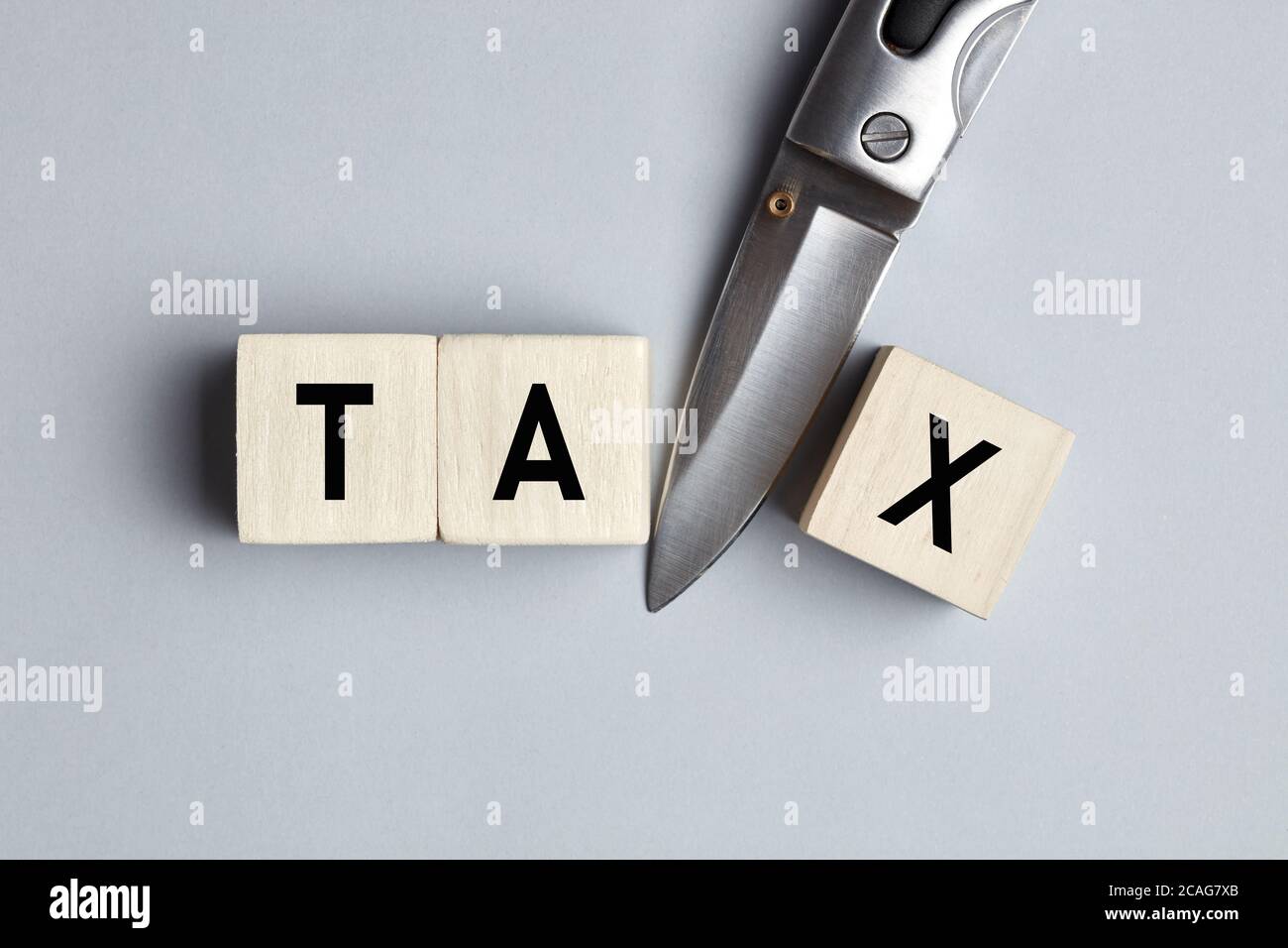 Das Wort Tax Cut auf Holzwürfel mit einem Messer geschrieben. Steuersenkungs-, Senkungs- oder Abzugskonzept. Stockfoto