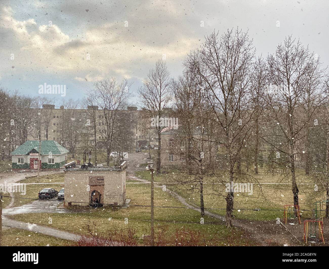 Plötzlicher heftiger Schneefall in einem städtischen Dorf mitten in einem sonnigen Frühlingstag Stockfoto