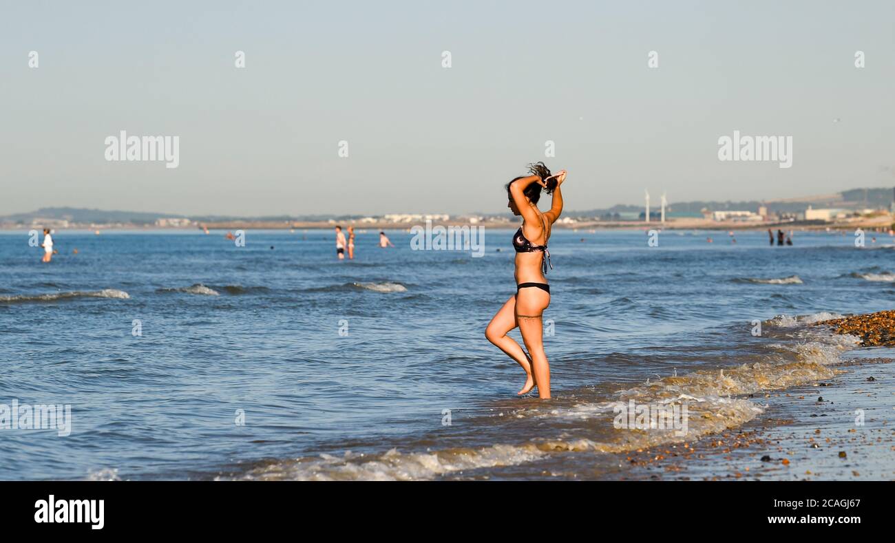 Brighton UK 7. August 2020 - EINE junge Frau geht in das Meer vor Brighton Strand früh am Morgen an einem anderen heißen sonnigen Tag, da die Temperatur prognostiziert wird, um die hohen 30 in einigen Teilen des Südostens heute zu erreichen : Credit Simon Dack / Alamy Live News Stockfoto