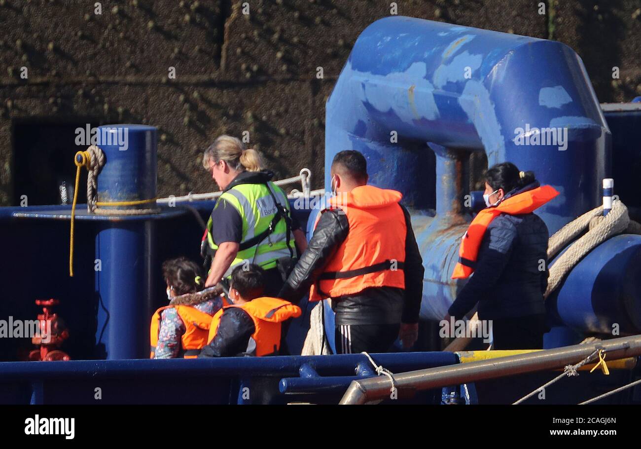 Ein Grenztruppen-Offizier begleitet eine junge Familie, die sich als Migranten von einem Grenztruppen-Schiff ausgibt, nachdem sie nach einer Reihe von kleinen Bootsvorfällen im Kanal nach Dover, Kent, gebracht wurden. Stockfoto