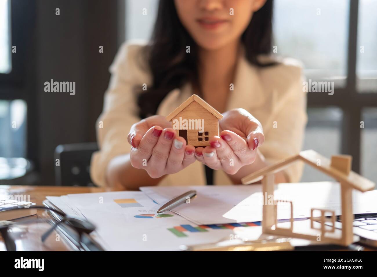 Immobilienmakler mit Hausmodell auf hans bieten Haus. Sachversicherung und Sicherheitskonzept Stockfoto