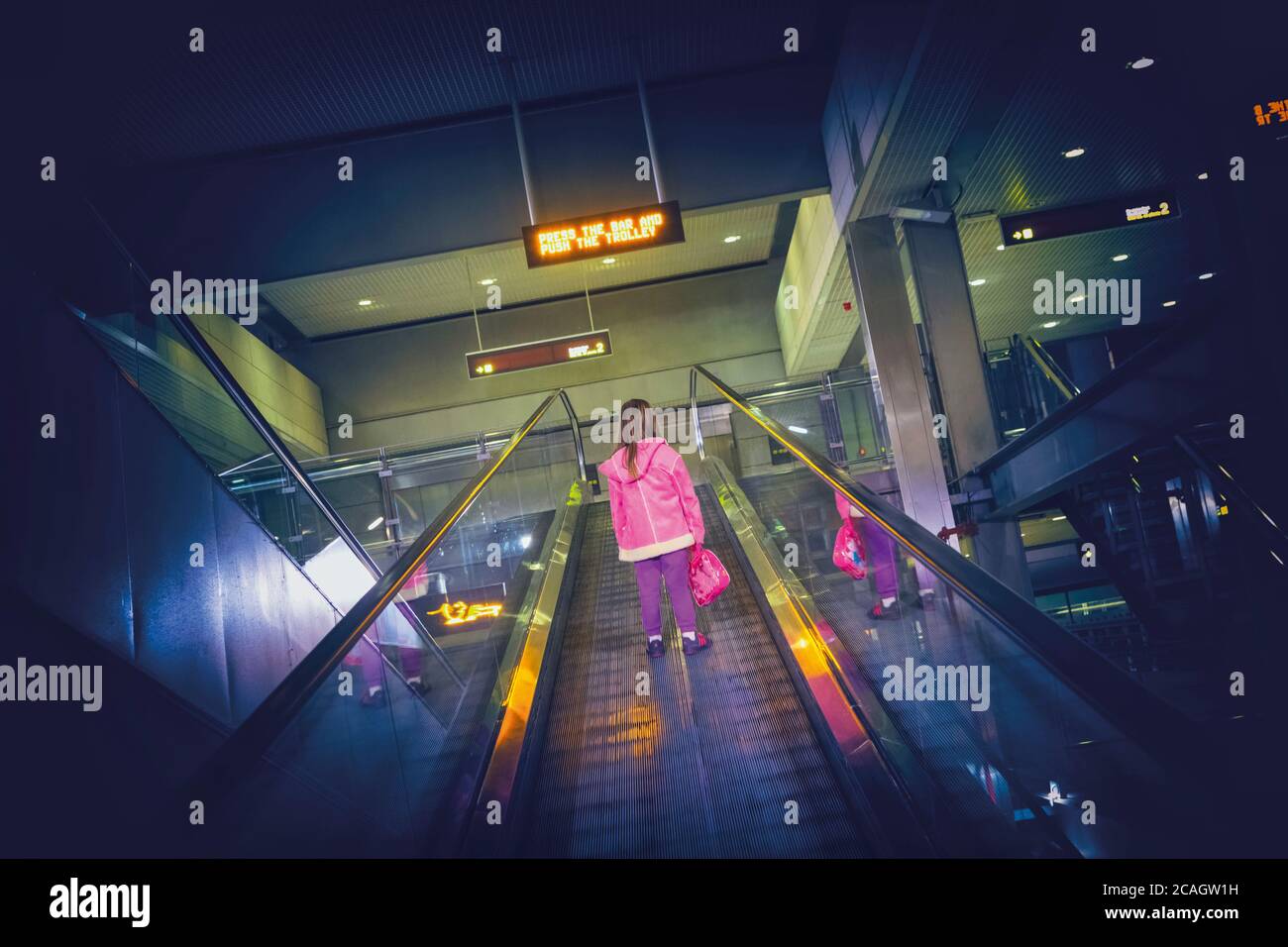 Kleines Kind allein auf der Rolltreppe im Flughafen. Stockfoto