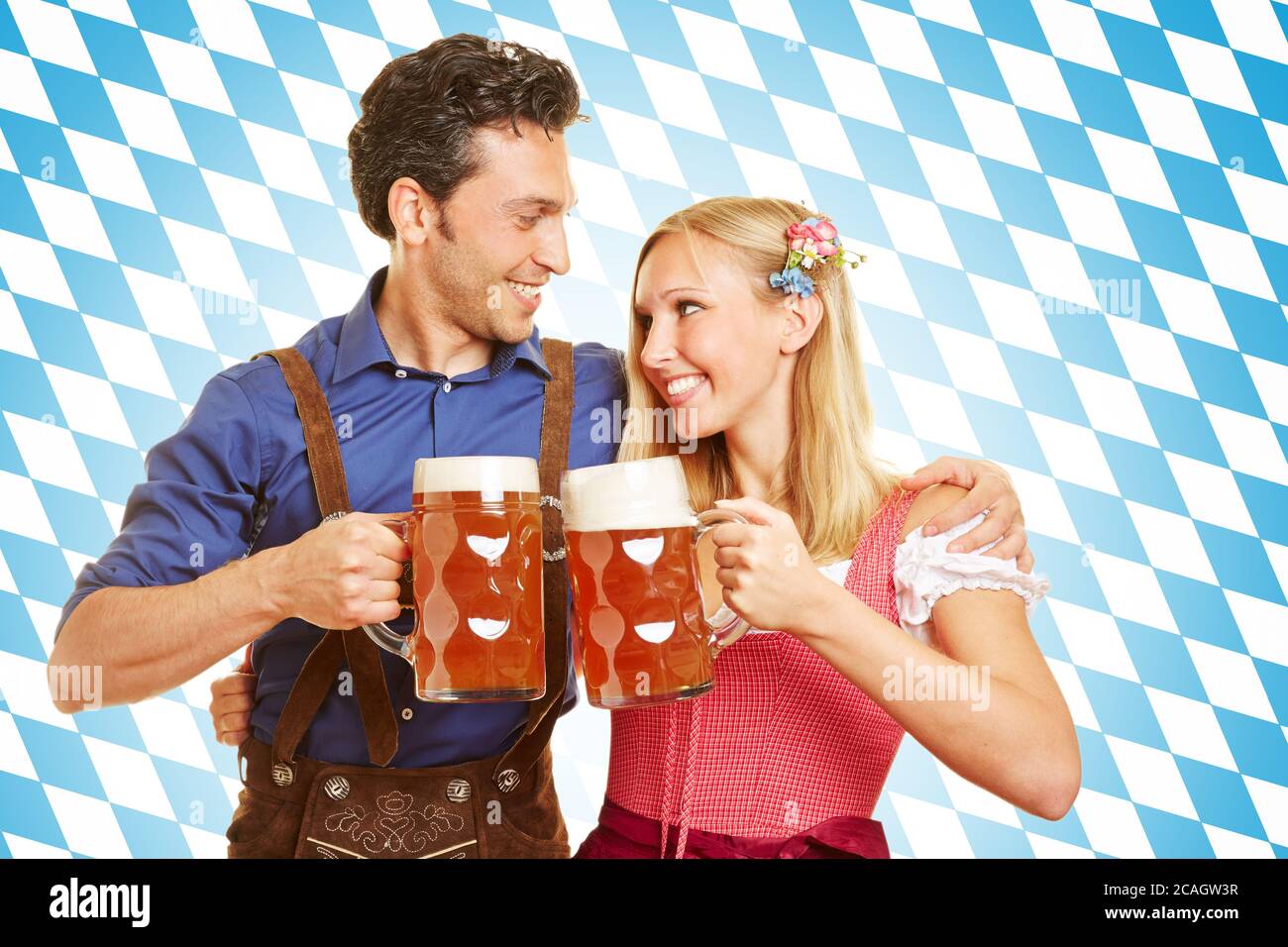 Fröhliches Paar beim Toasten mit Bier in bayerischer Tracht zum Oktoberfest Stockfoto