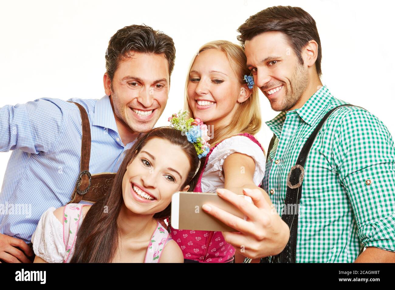 Vier glückliche Freunde im bayerischen Kostüm fotografieren mit dem Smartphone Stockfoto