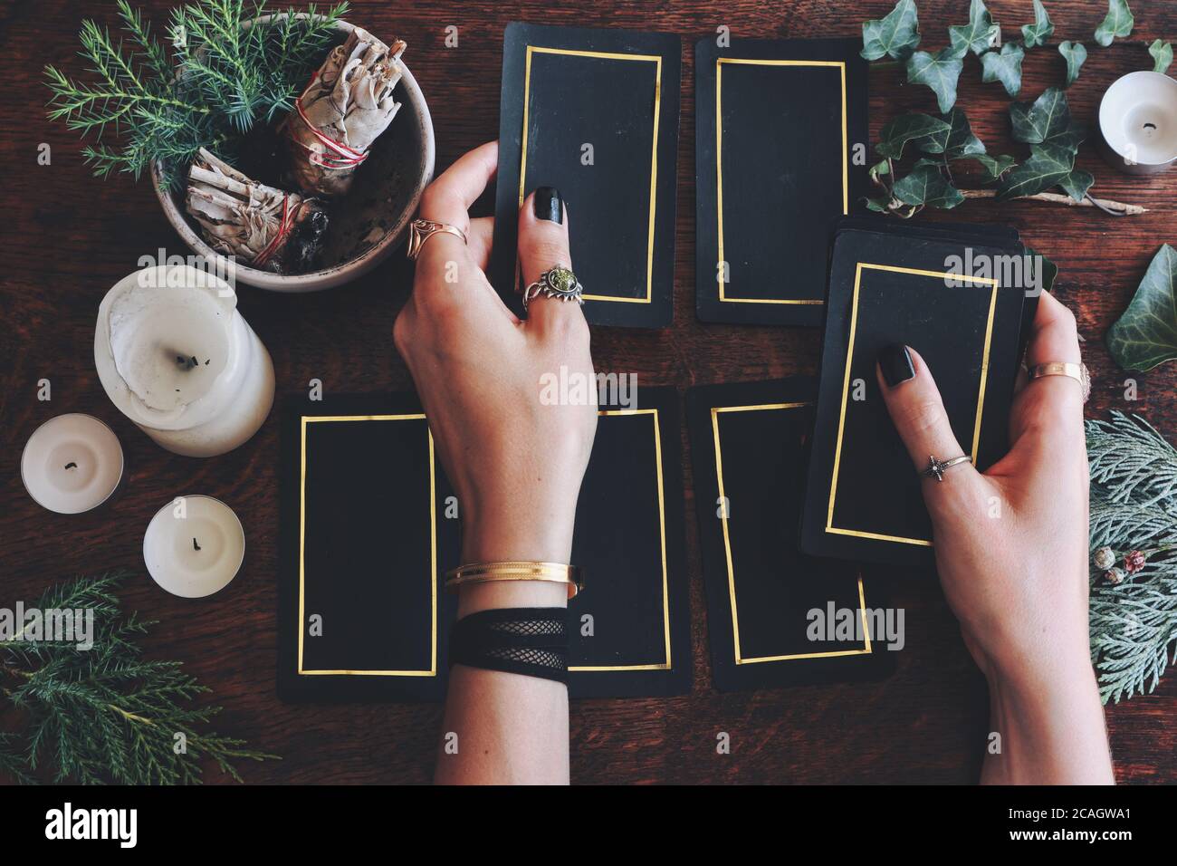 Wiccan Hexe tun eine Tarot-Karte lesen, um die Zukunft vorherzusagen. Weibliche Hände halten Hand gemacht Tarot Kartendeck. Schwarze Karten mit goldenem Rand Stockfoto