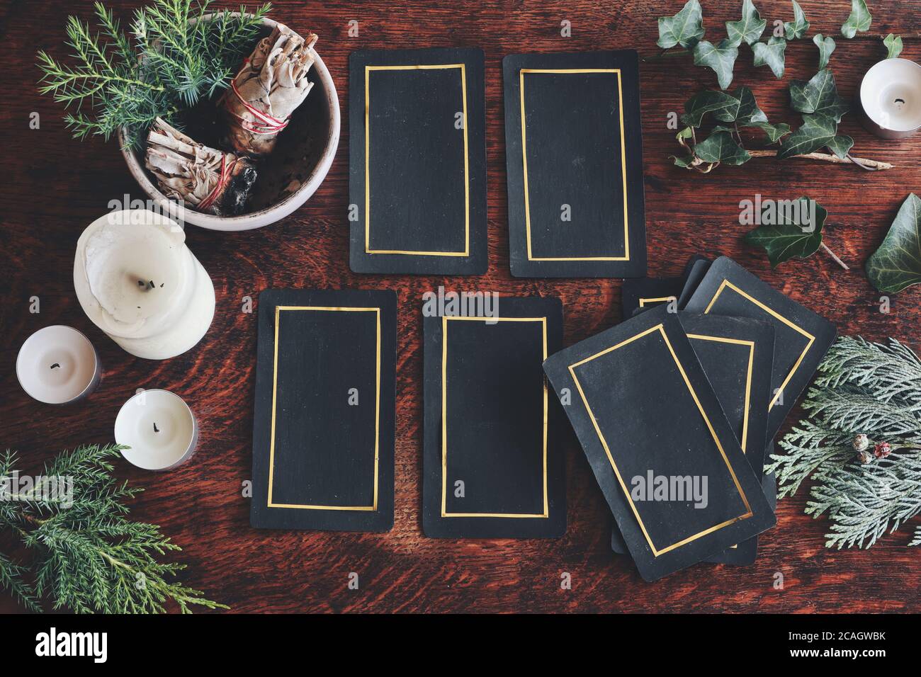 Tarot 4 Karte ausgebreitet auf einem Naturschaugerät gelegt (flaches Lay) . Handgemachte Tarot-Karten auf einem dunklen Holztisch, umgeben von Evergreens, Efeu, Salbei-Sticks Stockfoto