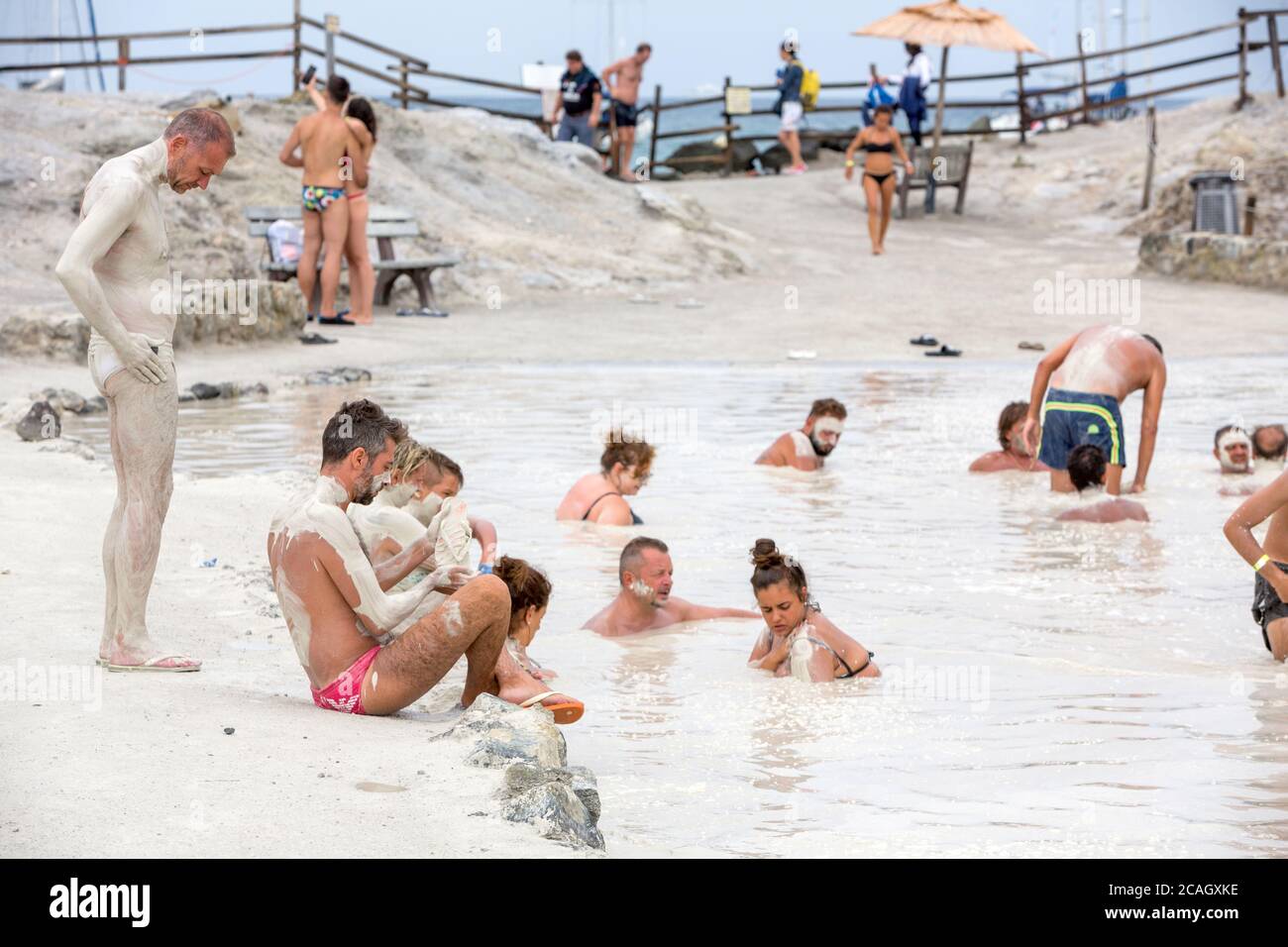 20.08.2018, Vulcano, Sizilien, Italien - Touristen und Einheimische nehmen ein Schwefelbad, Heilbad im Schwefelschlamm. Im Hintergrund das Meer. Vulcano b Stockfoto