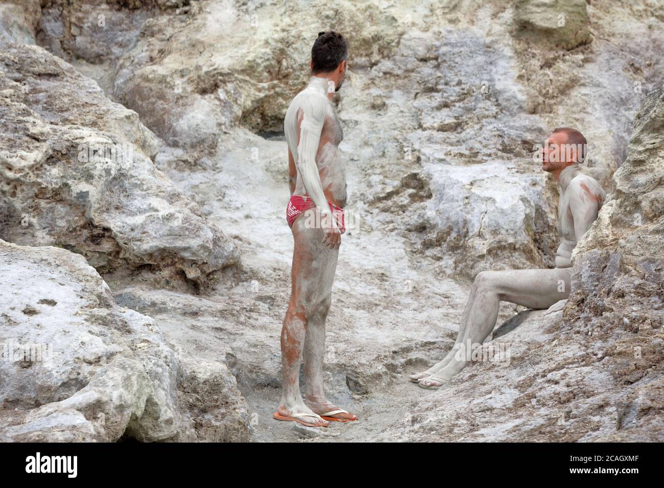 20.08.2018, Vulcano, Sizilien, Italien - Touristen und Einheimische nehmen ein heilendes Schwefelbad. Der Schwefelschlamm trocknet in den warmen Steinhöhlen. Vulcano gehört zu t Stockfoto