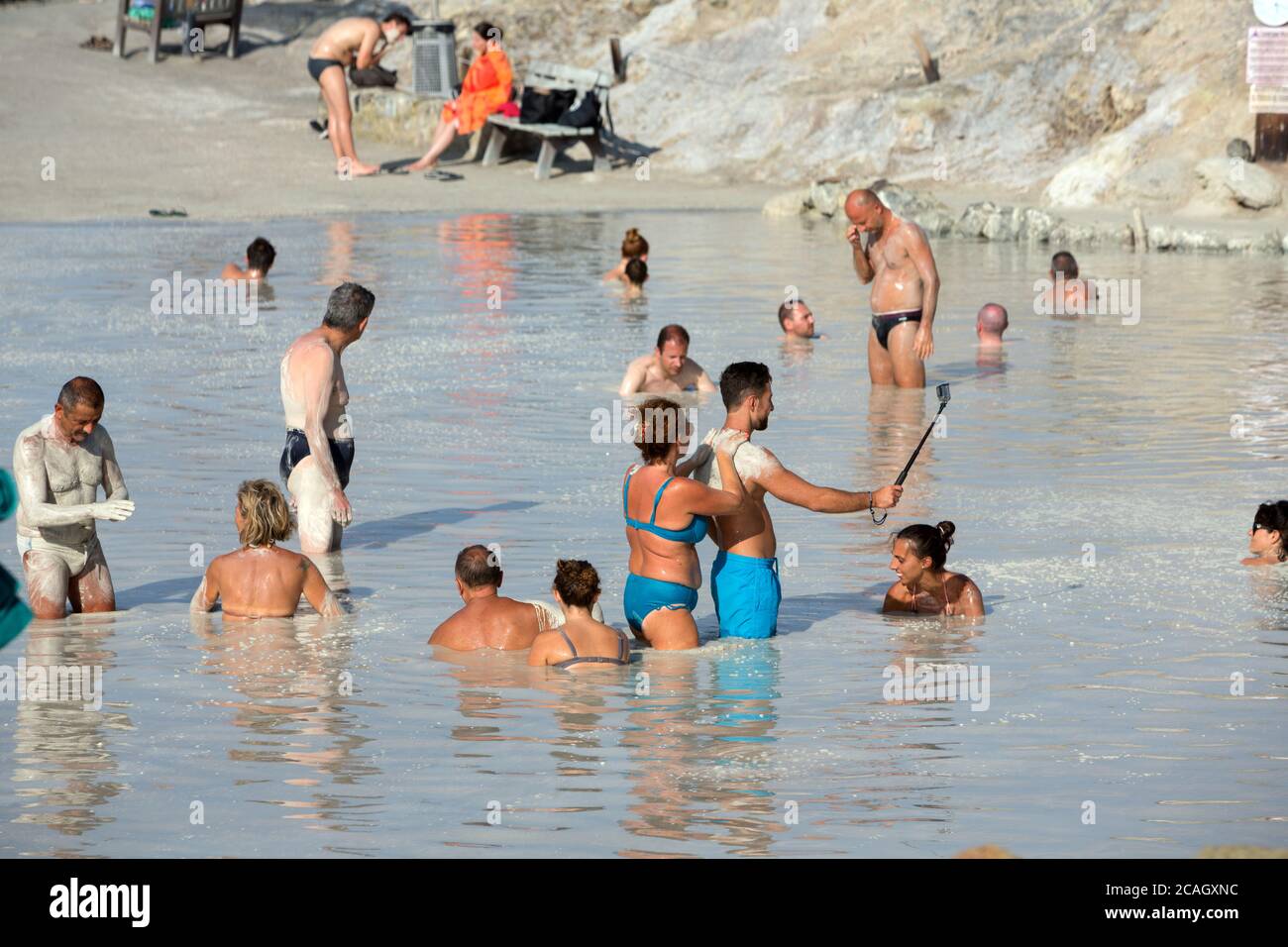 20.08.2018, Vulcano, Sizilien, Italien - Touristen und Einheimische nehmen ein Schwefelbad, ein Heilbad im Schwefelschlamm. Ein Mann filmt sich mit seinem Smartphone o Stockfoto