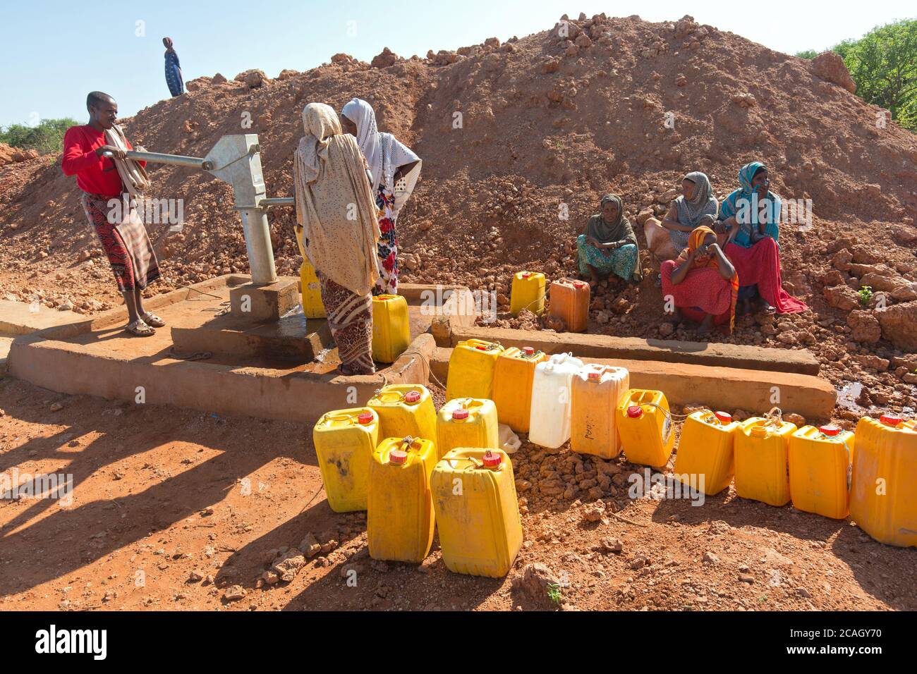 13.11.2019, Gabradahidan, Somali Region, Äthiopien - Frauen füllen gelbe Wasserkanister an einer Wasserpumpe. Ein Mann pumpt mit dem HE Wasser aus einer Zisterne Stockfoto