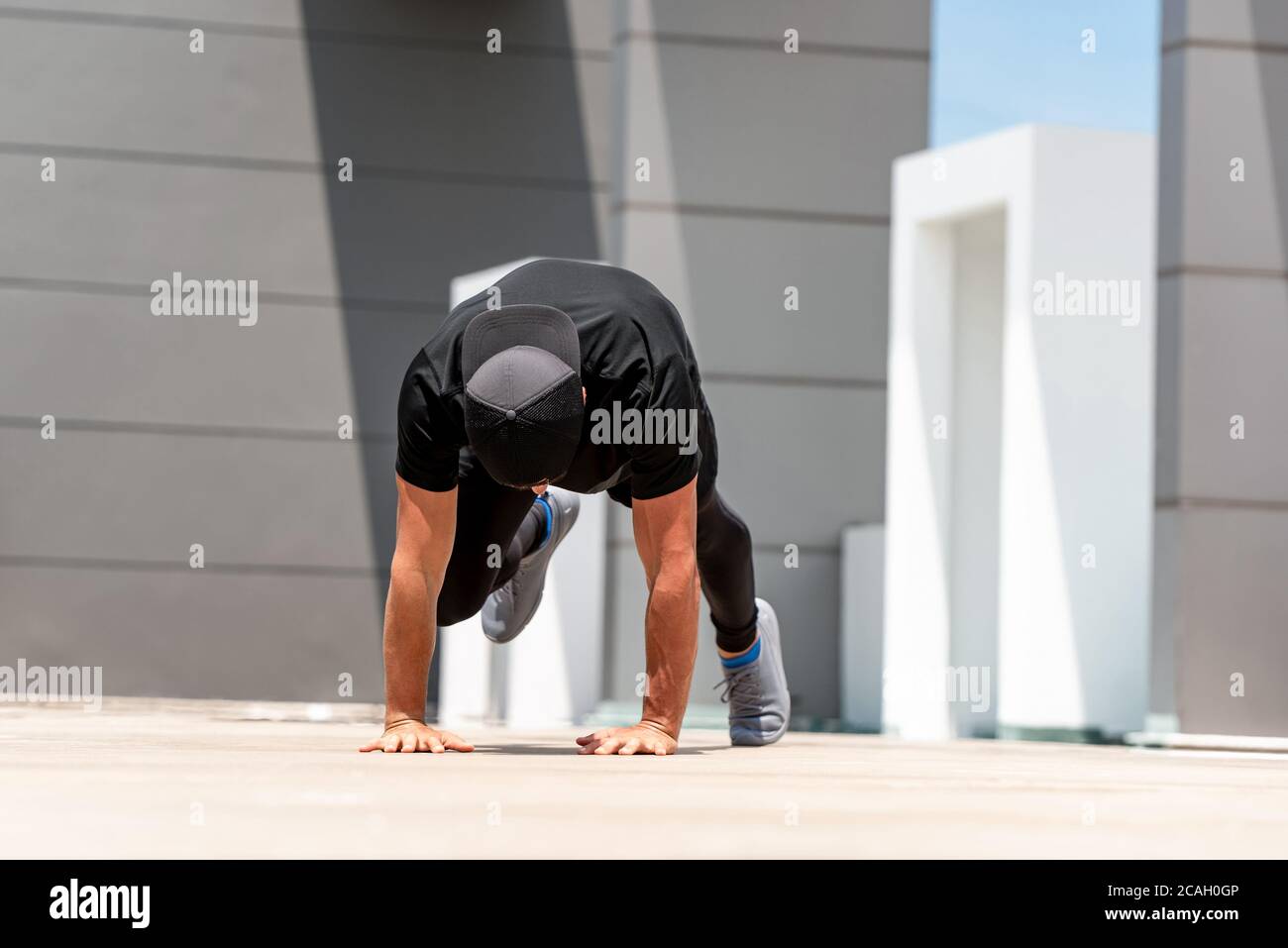 Fit Sport Mann tun Bergsteiger Übung im Freien auf Gebäude Dachboden in Sonnenlicht Stockfoto