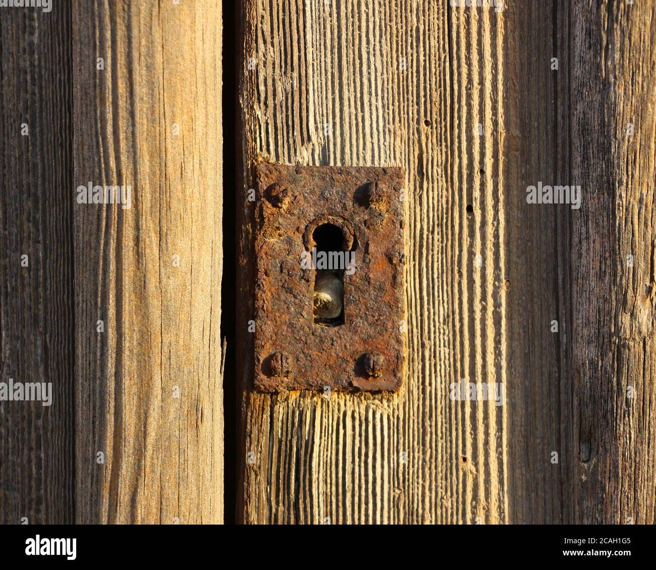 Alte verrostete Schlüssellochblende an einer verwitterten Holztür Stockfoto