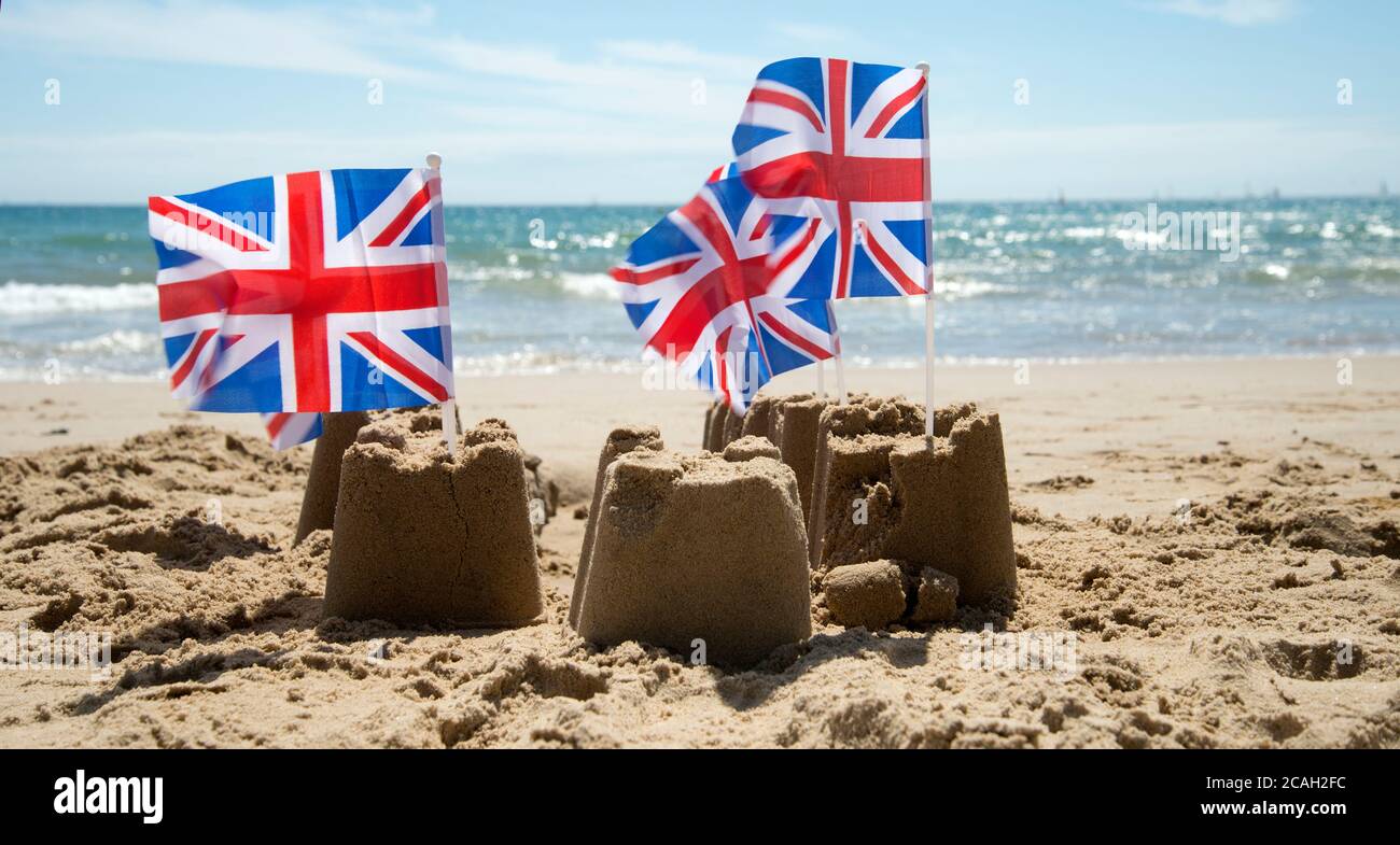 Sommer in Dorset. Poole. Zerbröckelnde Sandburgen mit Union Jacks Stockfoto