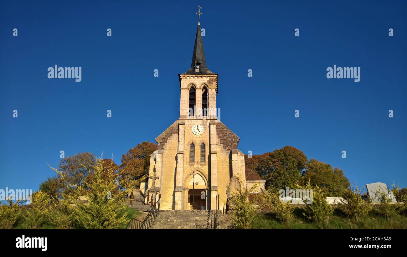 Eine alte Kirche steht stolz vor einem klaren blauen Himmel An einem ruhigen Herbsttag in Frankreich Stockfoto