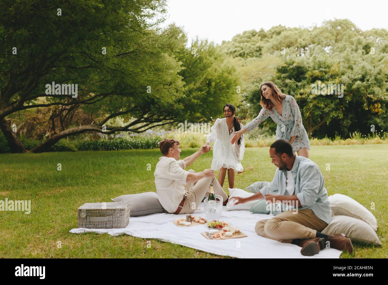 Eine Gruppe von Freunden, die im Park picknicken. Multiethnische Gruppe von jungen Menschen im Park mit Picknick. Stockfoto