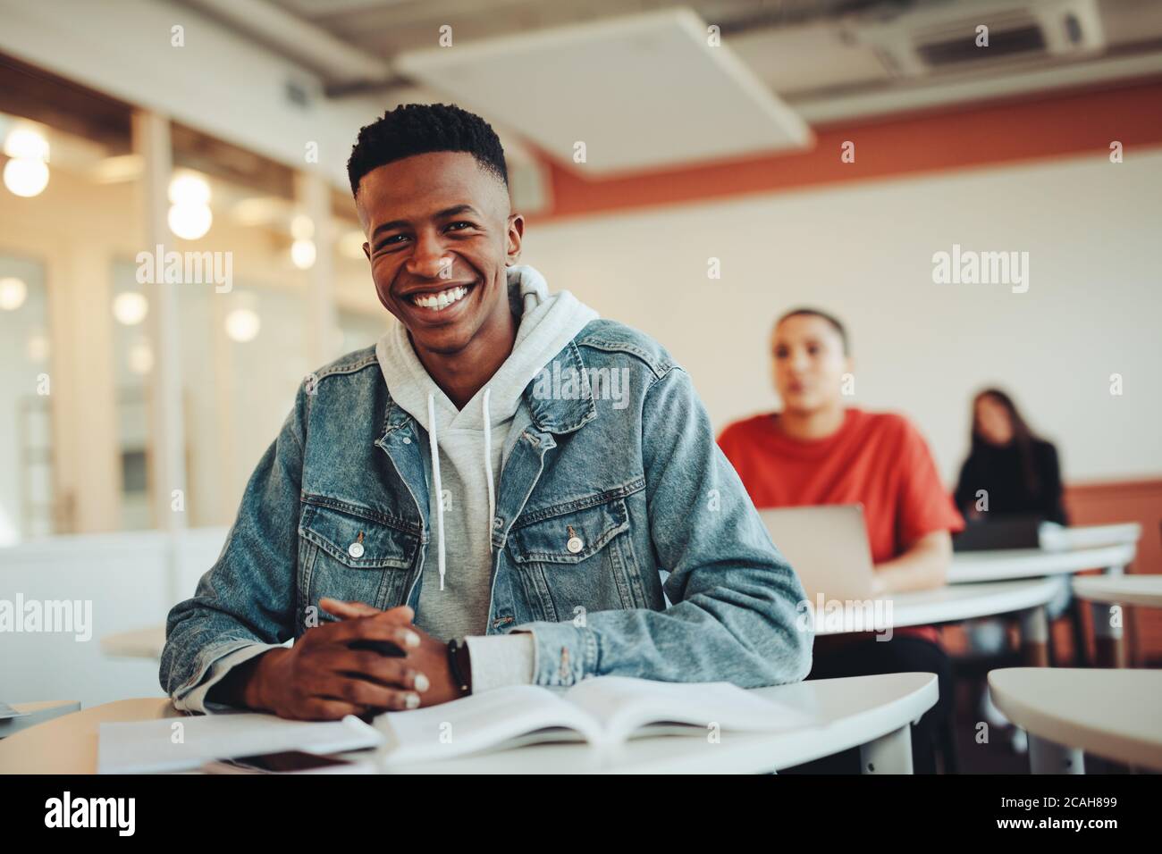 Porträt eines lächelnden Jungen im Klassenzimmer der Universität mit Blick auf die Kamera. Junger Mann in der Vorlesung an der High School. Stockfoto