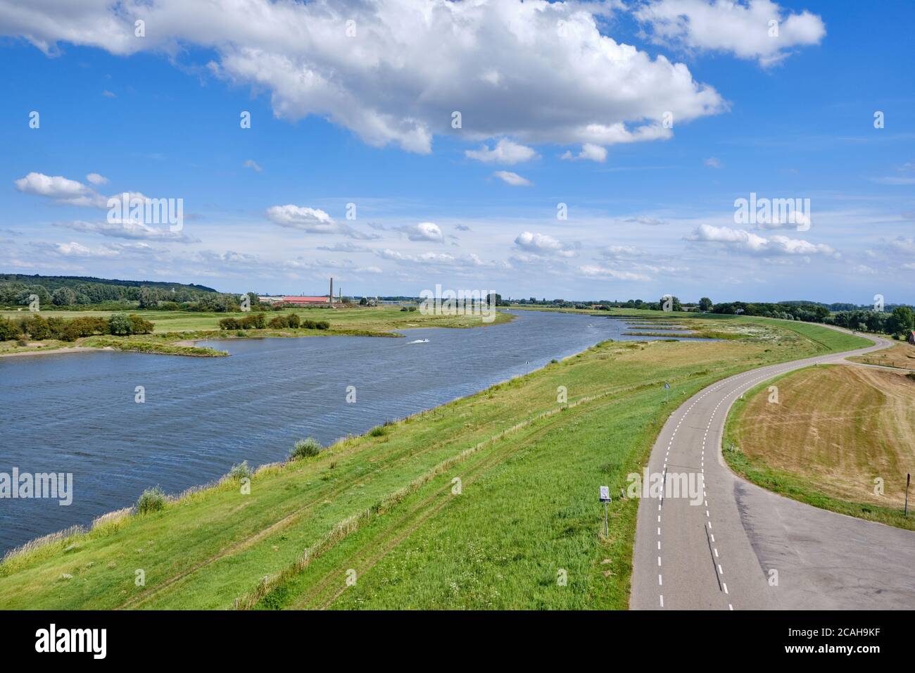 Typisch holländische Flusslandschaft mit Kühen, Grünland, Auen, Deich mit Straße und dem Rhein mit Groyne in Flussbiegung bei Wageningen Stockfoto