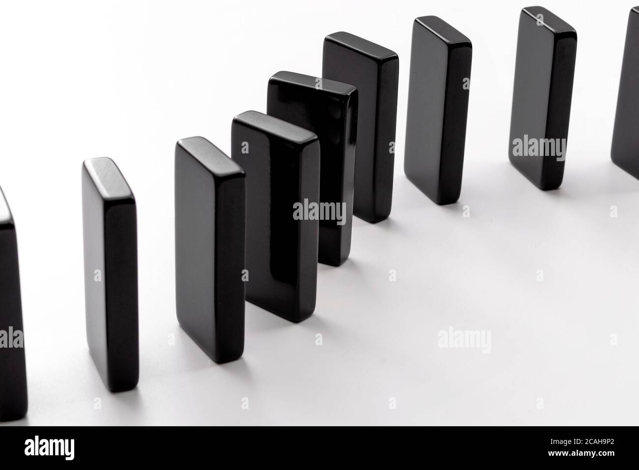 Metapher für Kettenreaktion und Welligkeit Effektkonzept mit Domino Fliesen stehen in einer Reihe isoliert auf weißem Hintergrund Stockfoto