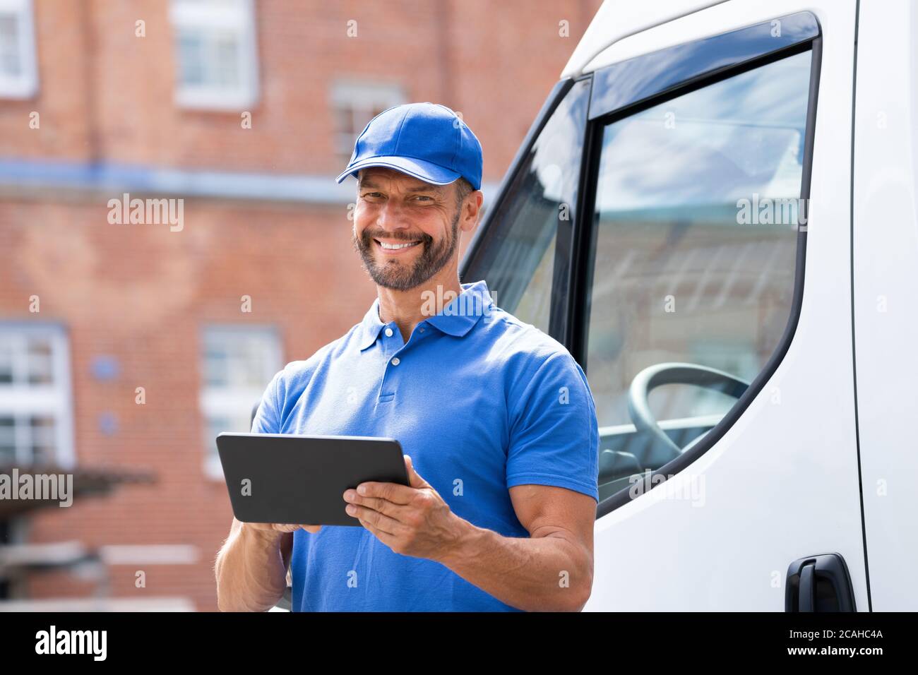 Delivery Man In Der Nähe Von Lkw Oder Van Mit Tablet Stockfoto