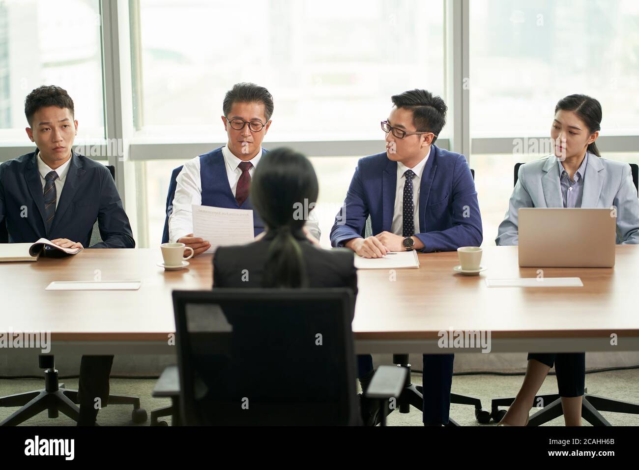 Junge asiatische Geschäftsfrau, die von einer Gruppe von Unternehmensleitern interviewt wird Stockfoto