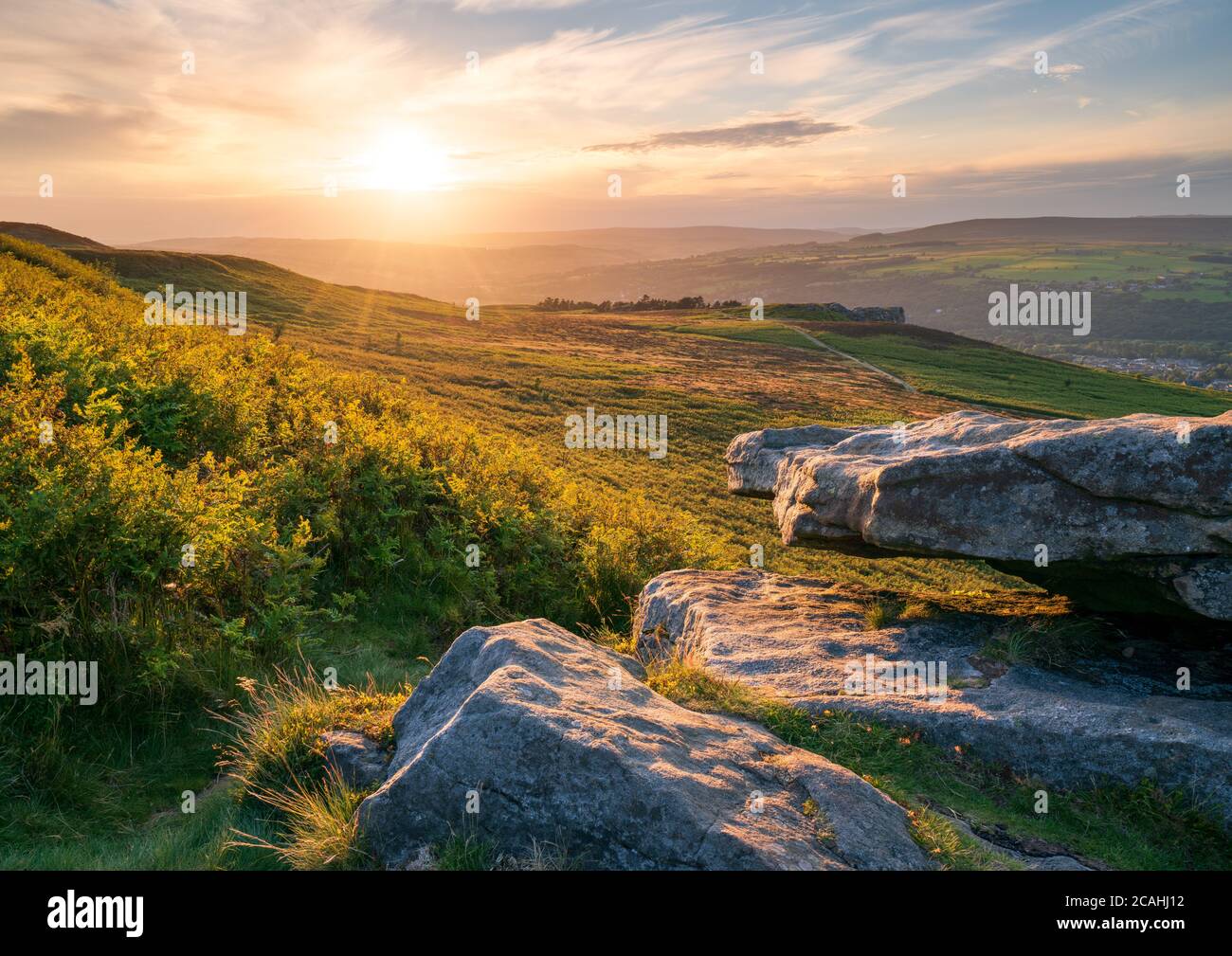 Der Blick vom Pancake Rock über Ilkley Moor mit der ikonischen Cow & Calf am Horizont bei strahlender Sonne zu Beginn der goldenen Stunde im Sommer. Stockfoto