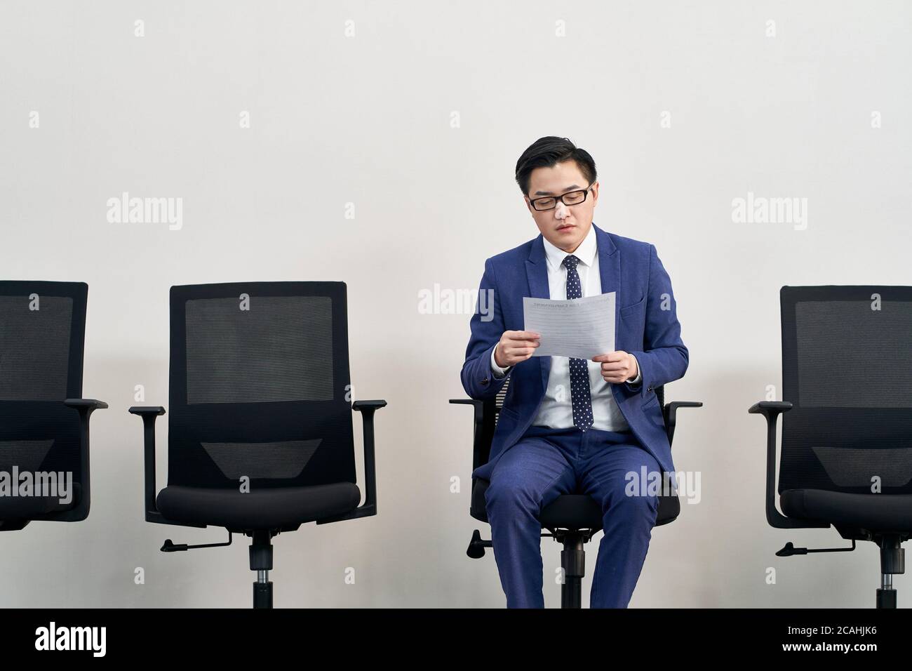 Junge asiatische männliche Arbeitssuchende Vorbereitung für Interview während warten in der Schlange Stockfoto