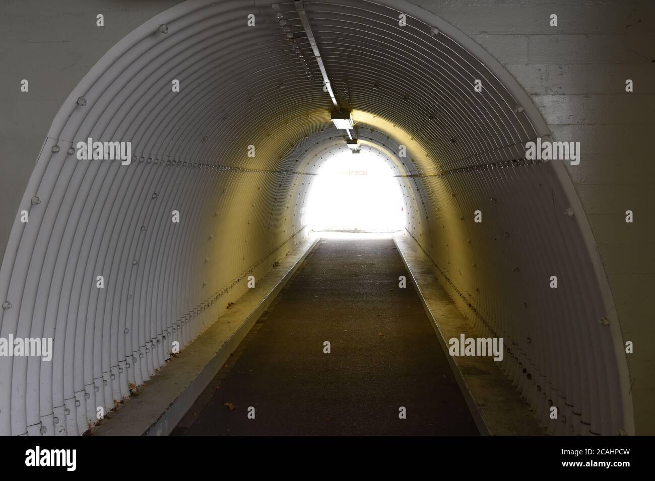 Städtische Fußgängerzone U-Bahn, Unterführung oder begehbare in Form eines weißen Tunnels mit Decke, Deckenlampen mit starkem, klarem Tageslicht am Ende Stockfoto